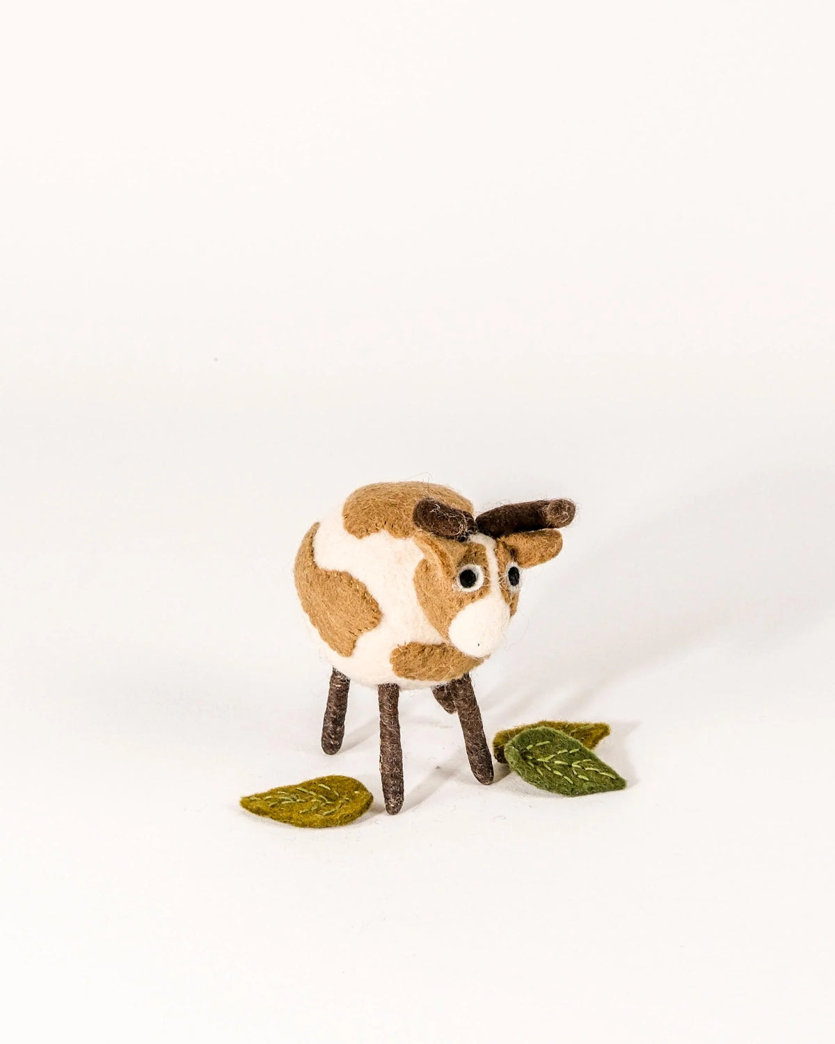 Grande vache marron en feutrine sur un fond blanc.
