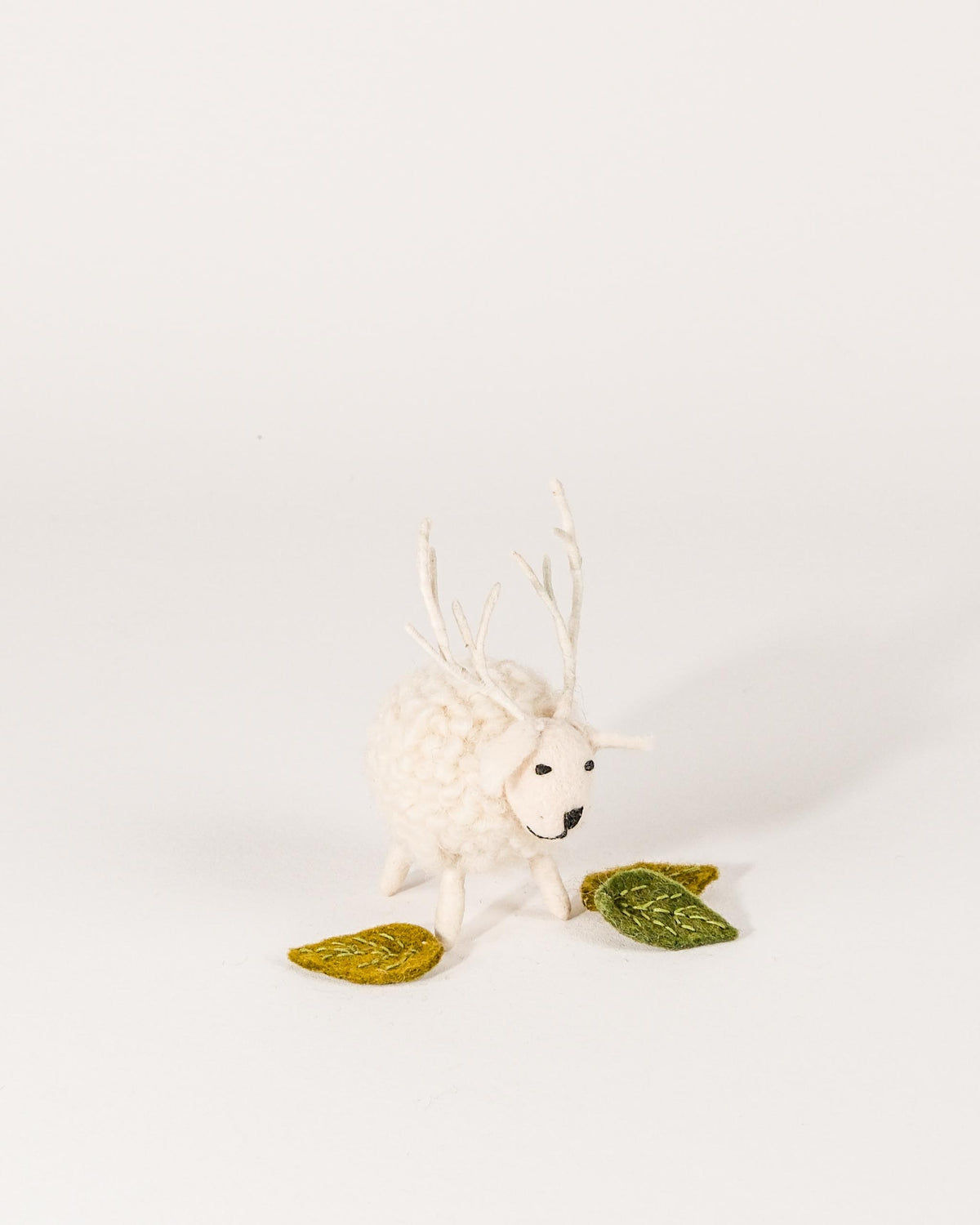 Petit cerf boule blanc en feutrine sur un fond blanc.
