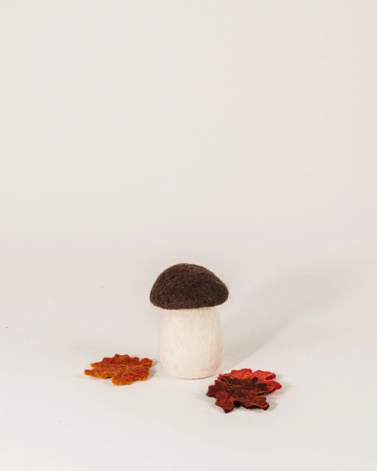 Grand champignon bolet marron en feutrine sur un fond blanc.