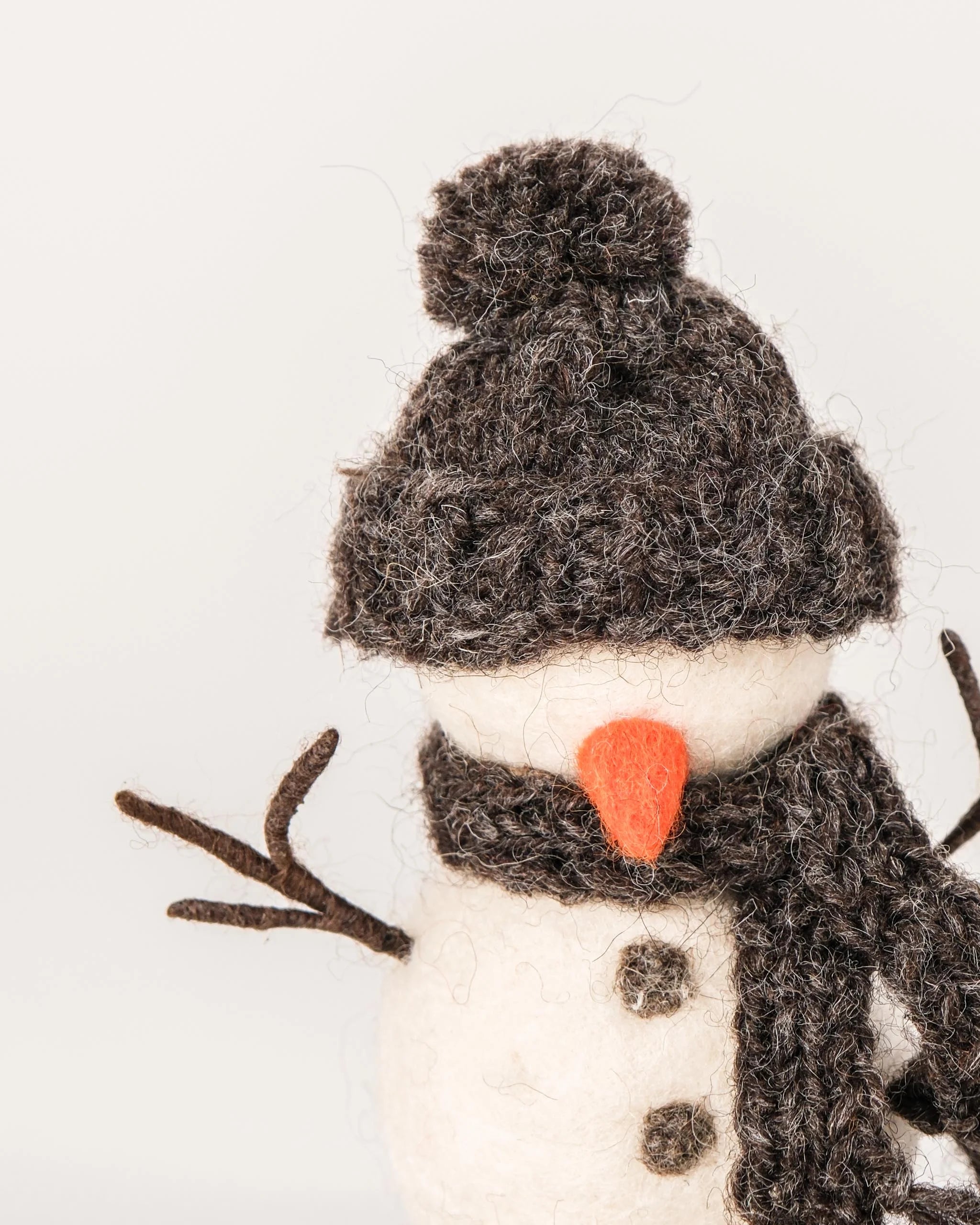 Petit bonhomme de neige en feutrine sur un fond blanc détail zoom matière.