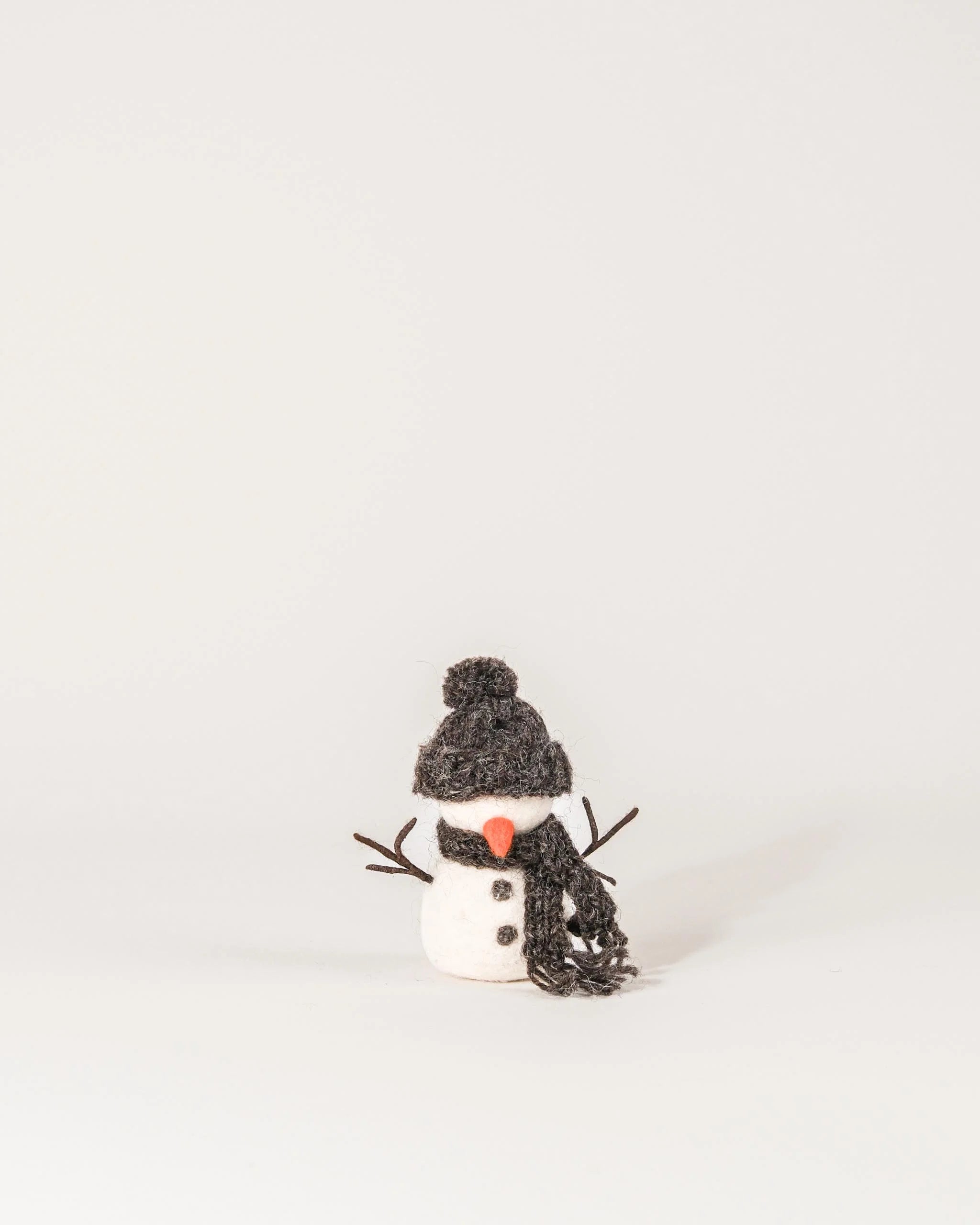 Petit bonhomme de neige en feutrine sur un fond blanc.