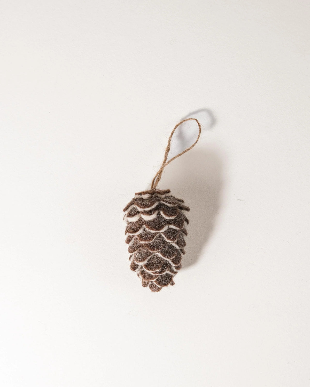 Pomme de pin simple en feutrine sur un fond blanc.