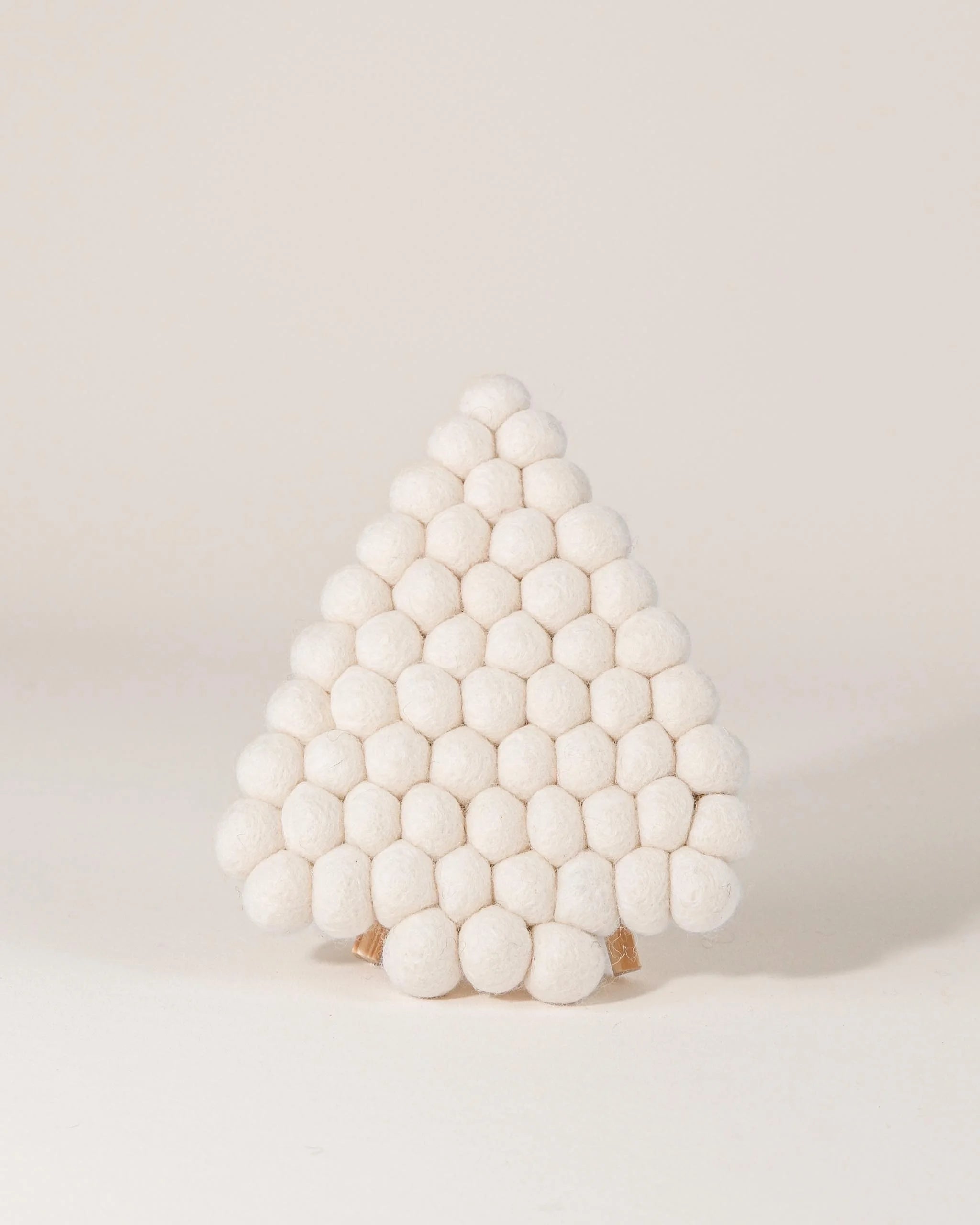 Dessous de plat boule en feutrine sapin blanc sur un fond blanc.