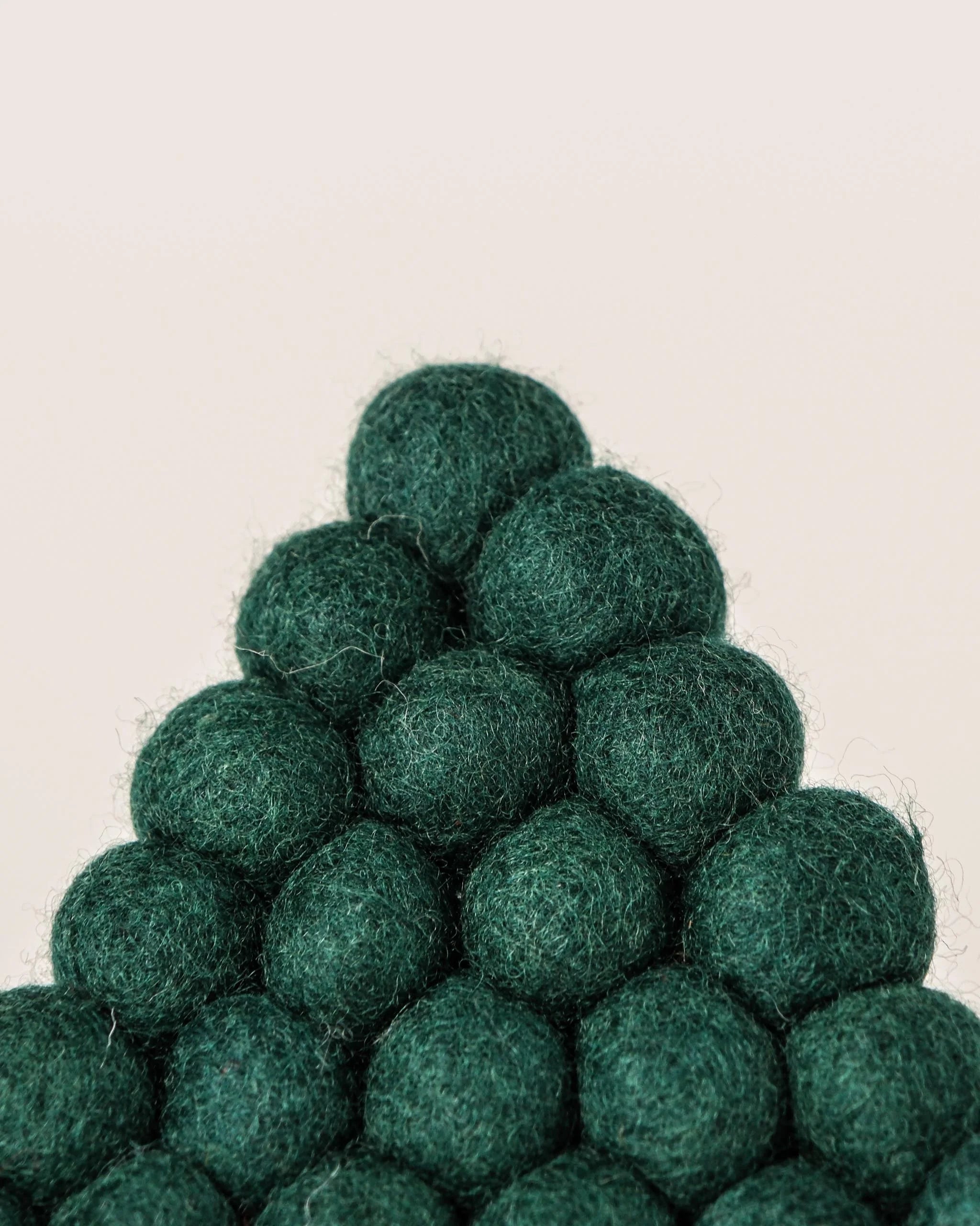 Dessous de plat boule en feutrine sapin vert sur un fond blanc zoom détail matiere.
