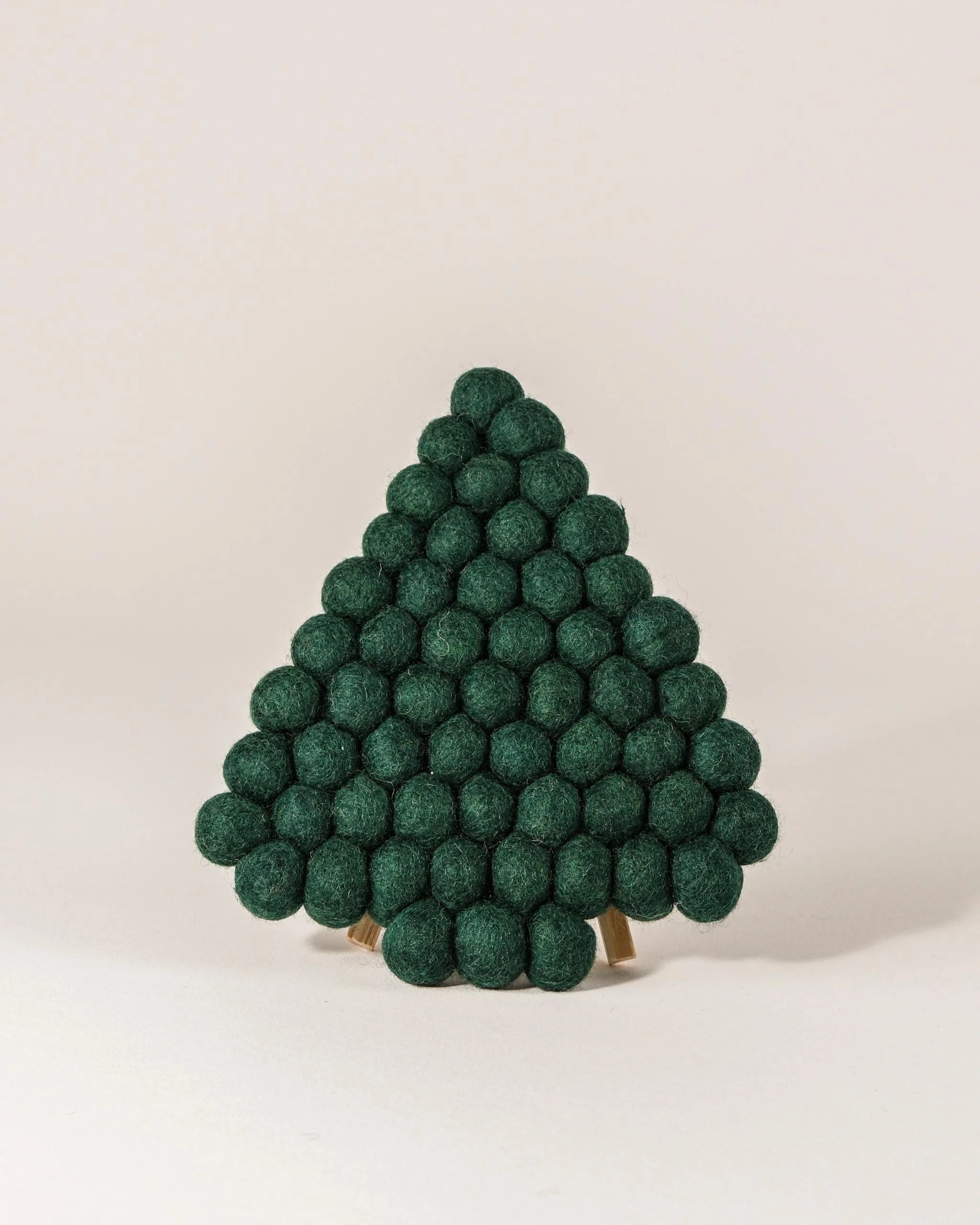 Dessous de plat boule en feutrine sapin vert sur un fond blanc.