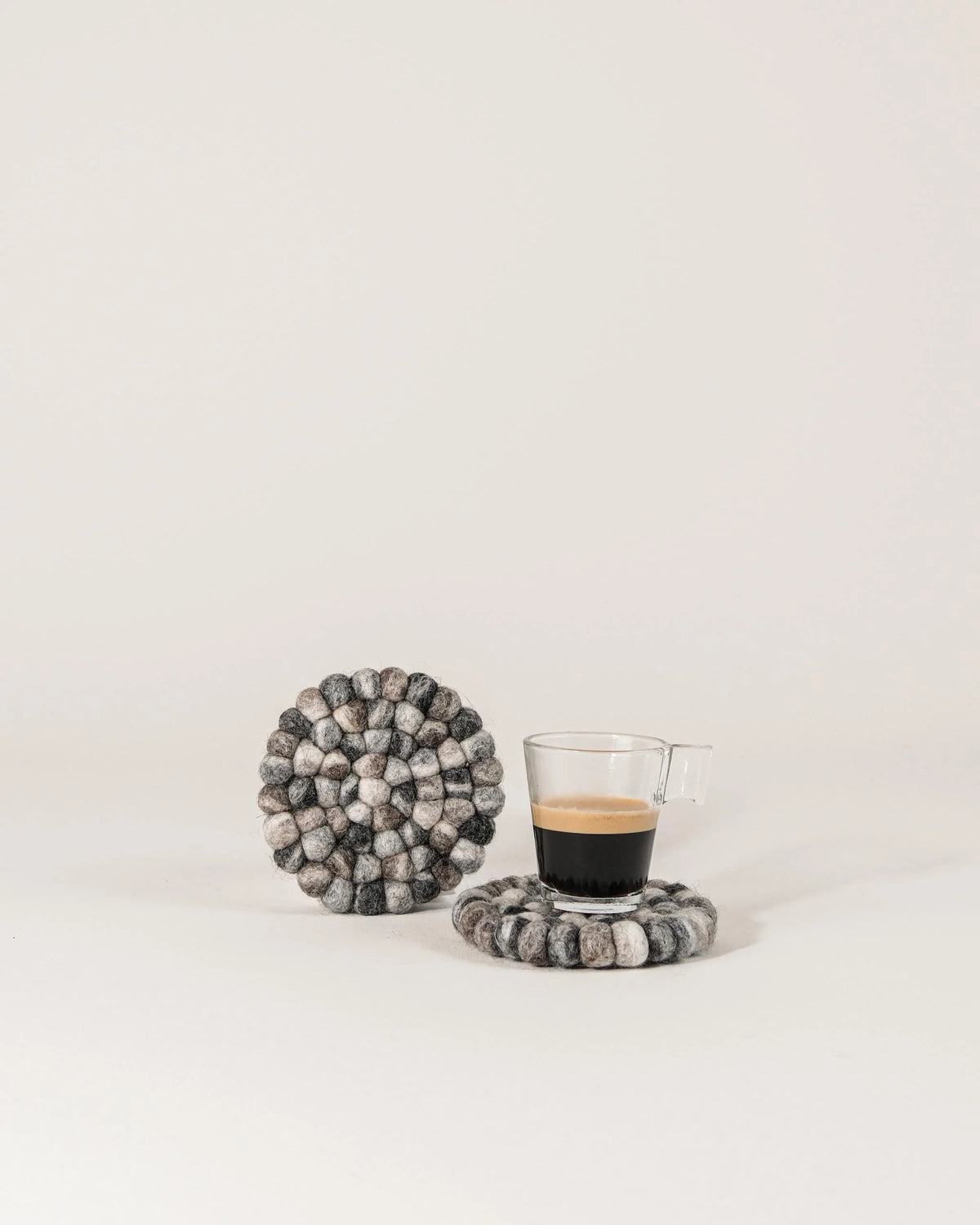 Set de 2 sous verre boule galet en feutrine sur un fond blanc.