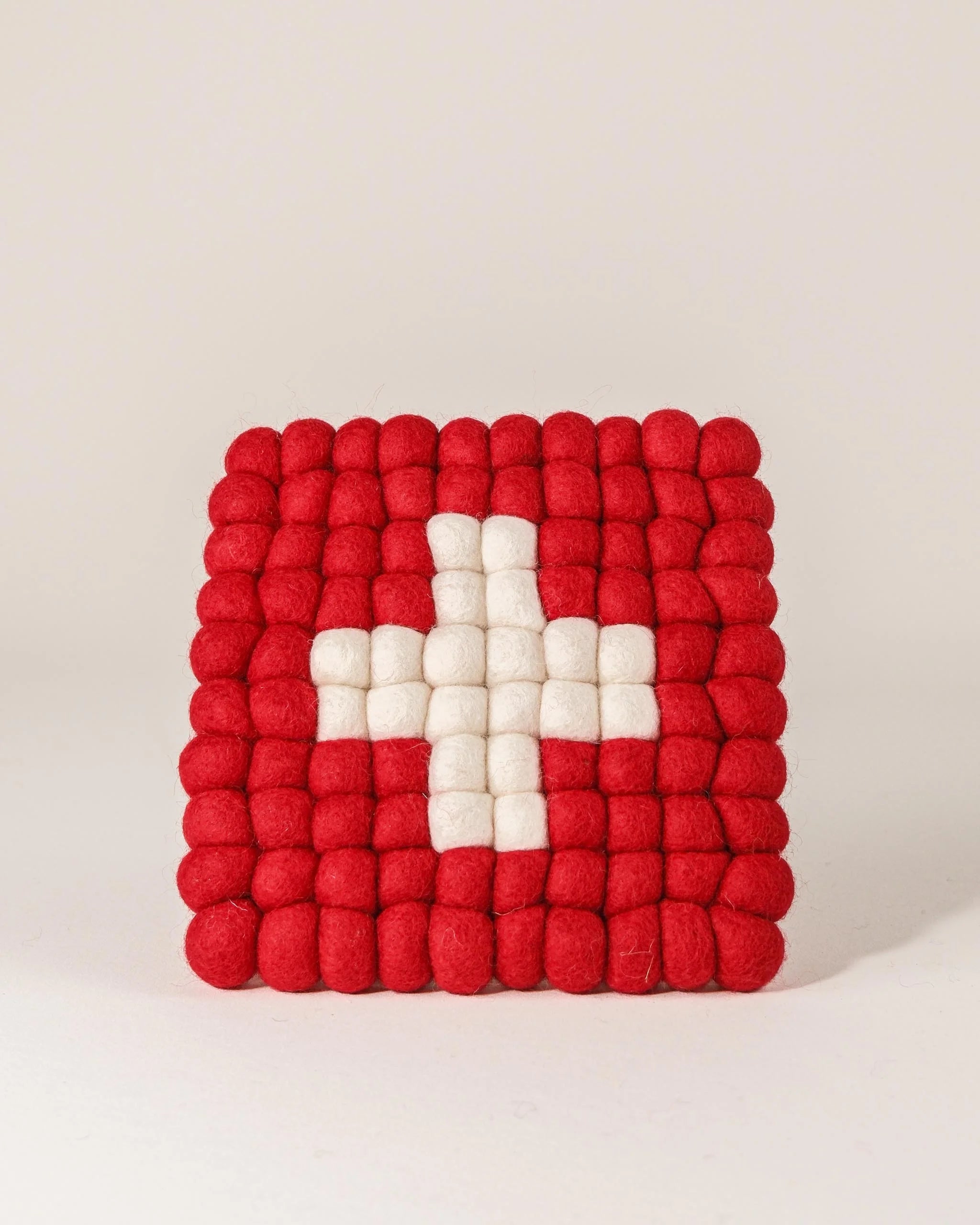 Dessous de plat boule en feutrine drapeau Suisse sur un fond blanc.