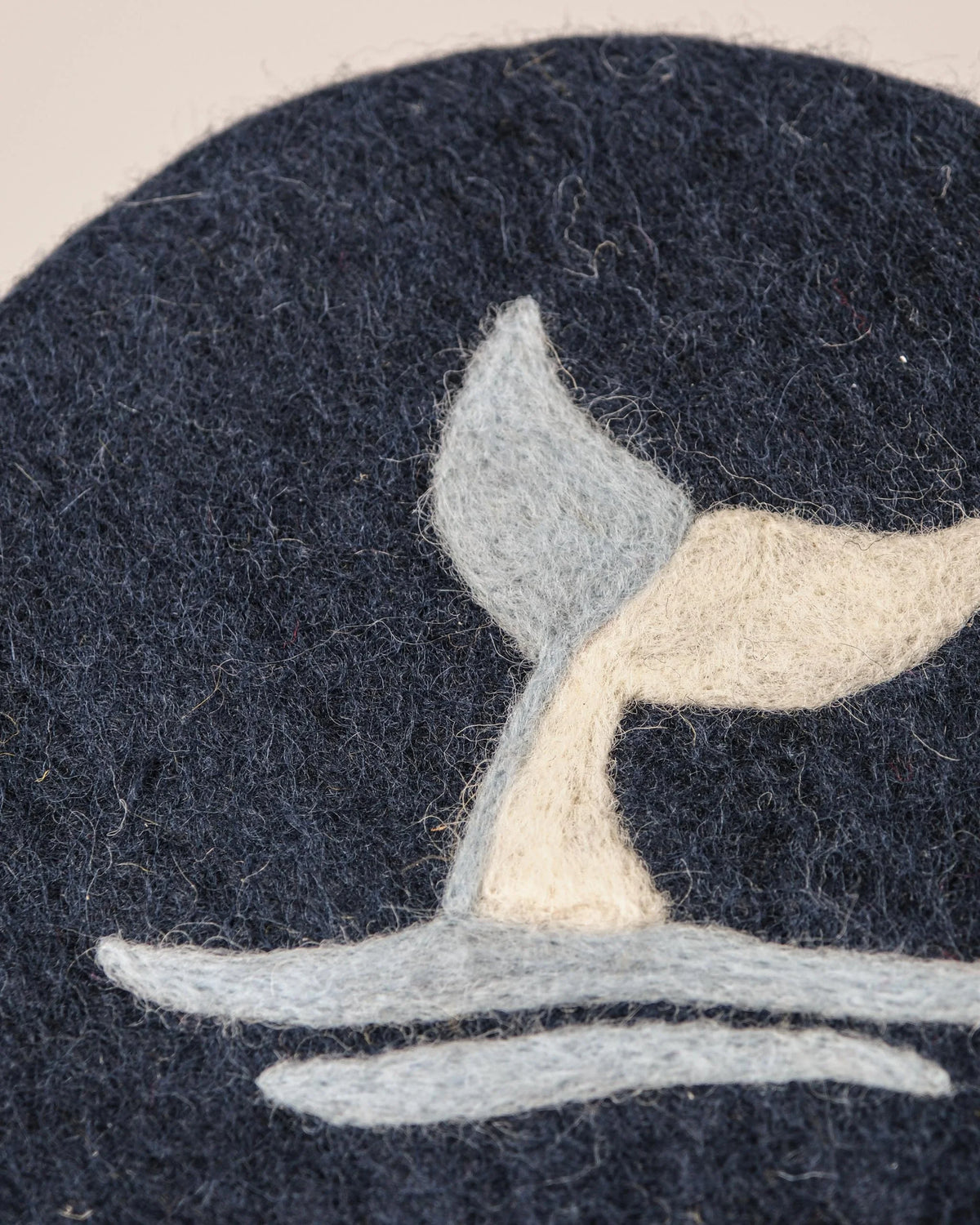 Dessous de plat boule en feutrine motif baleine sur un fond blanc détail zoom matière.