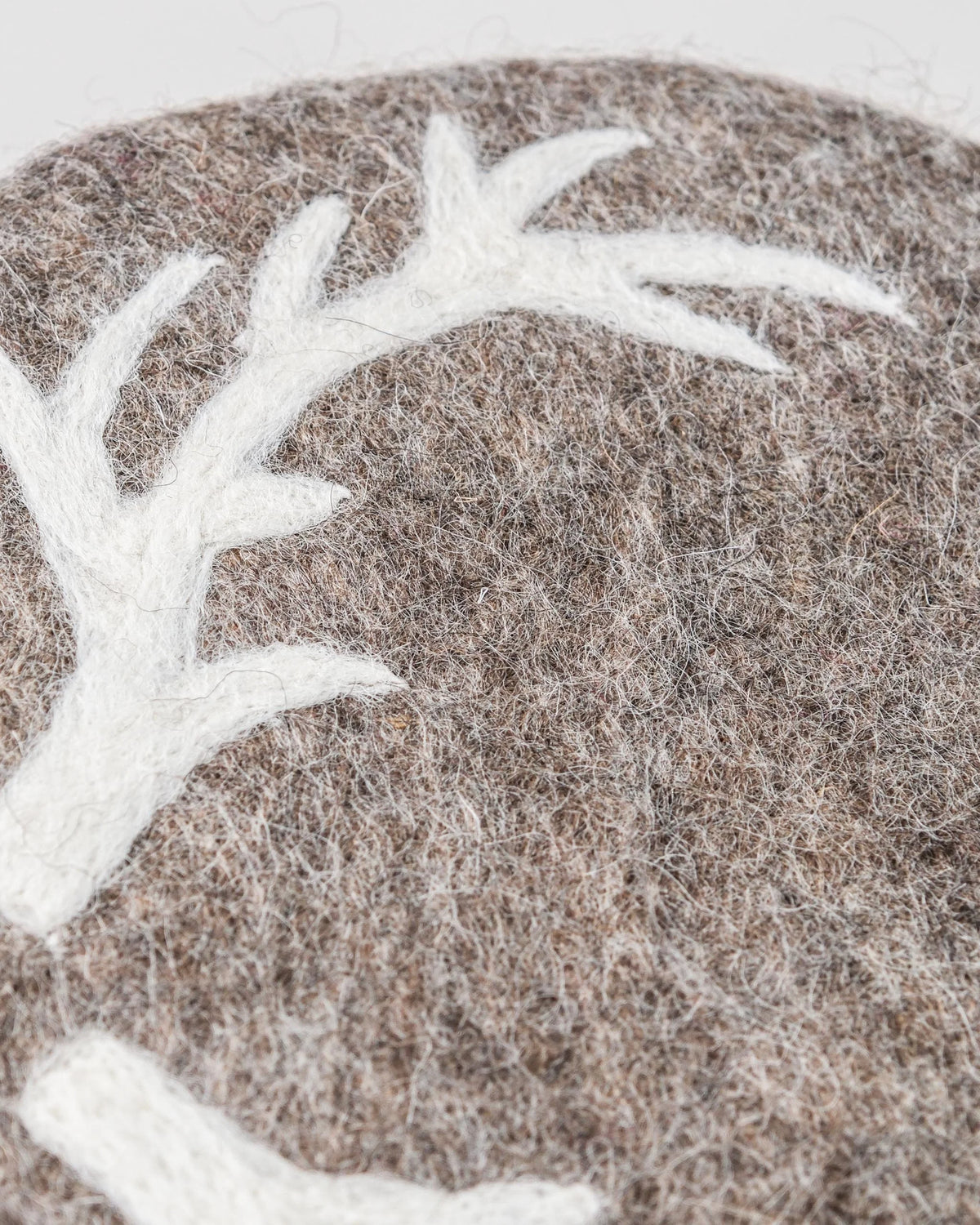 Dessous de plat boule en feutrine motif cerf sur un fond blanc détail zoom matière.