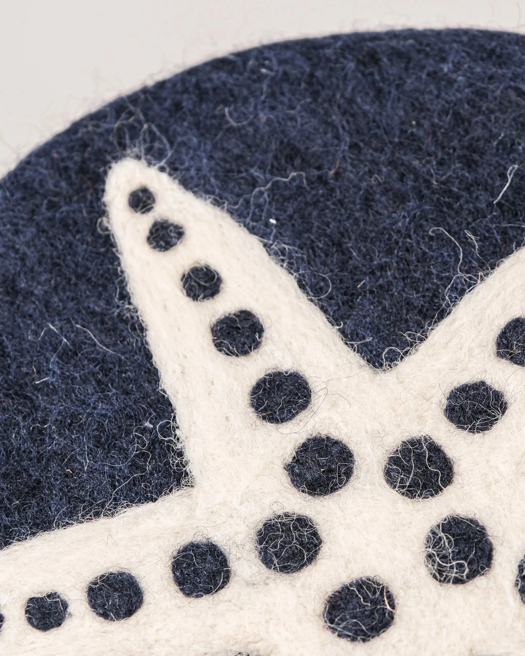 Dessous de plat boule en feutrine motif étoile de mer sur un fond blanc détail zoom matière.