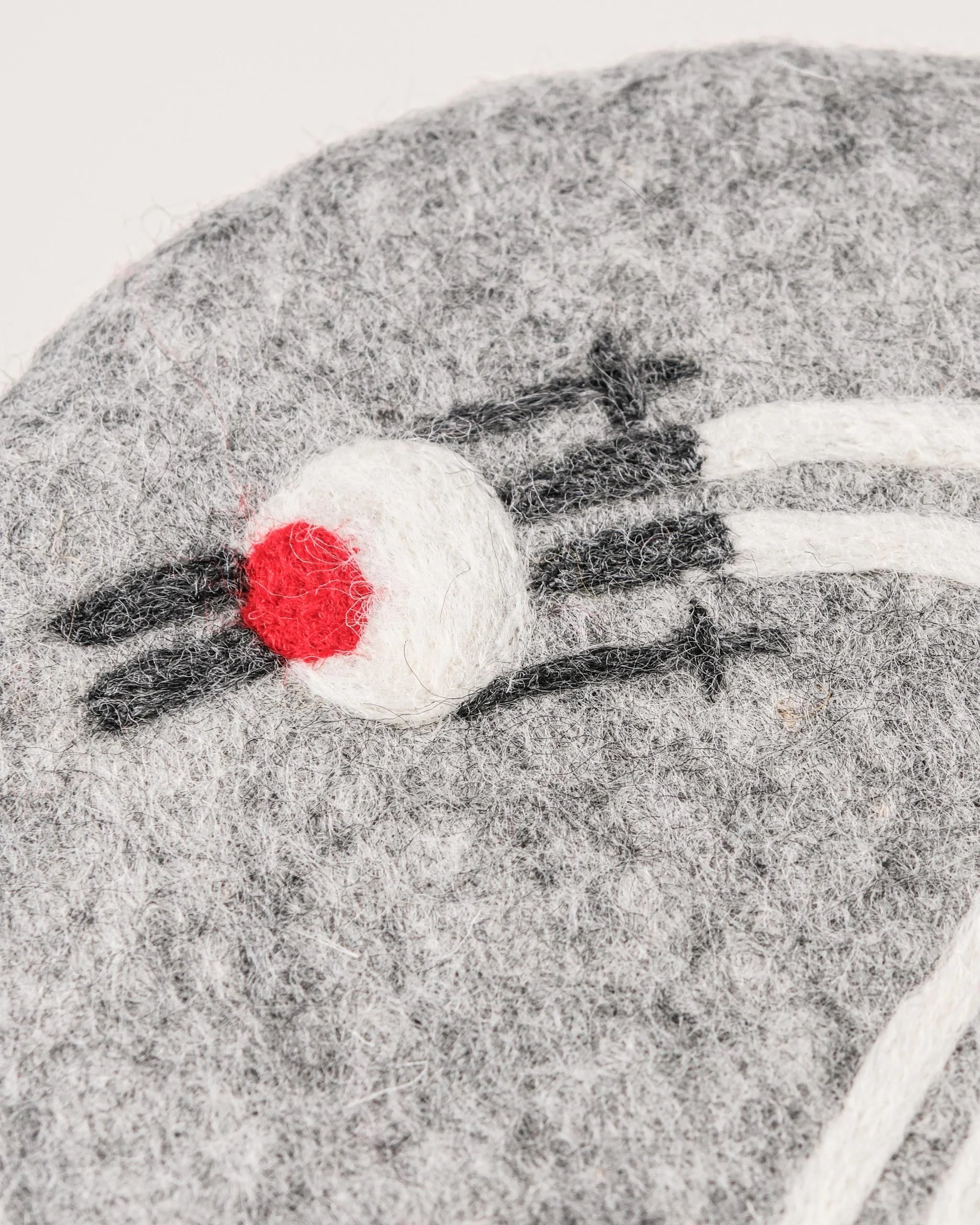 Dessous de plat boule en feutrine motif ski sur un fond blanc détail zoom matière.