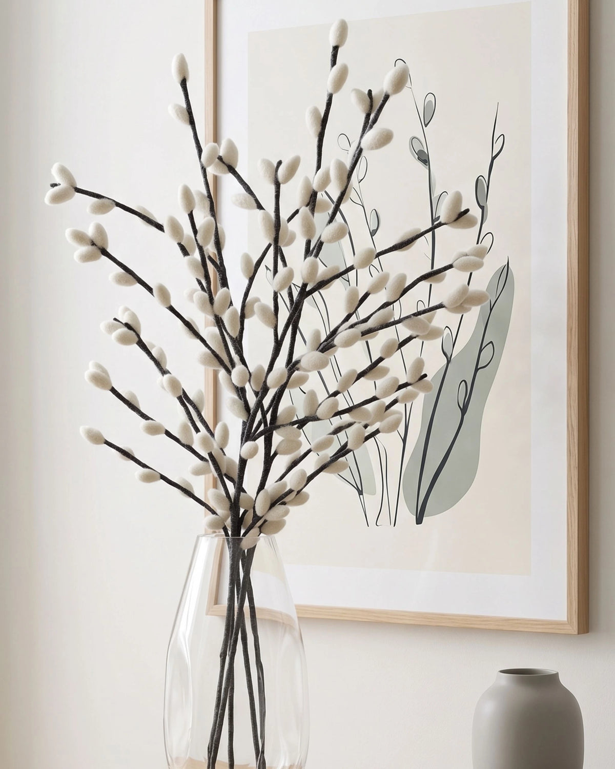 Bouquet de chaton de saule géant gris en feutrine dans un vase transparent avec un joli cadre dérière.