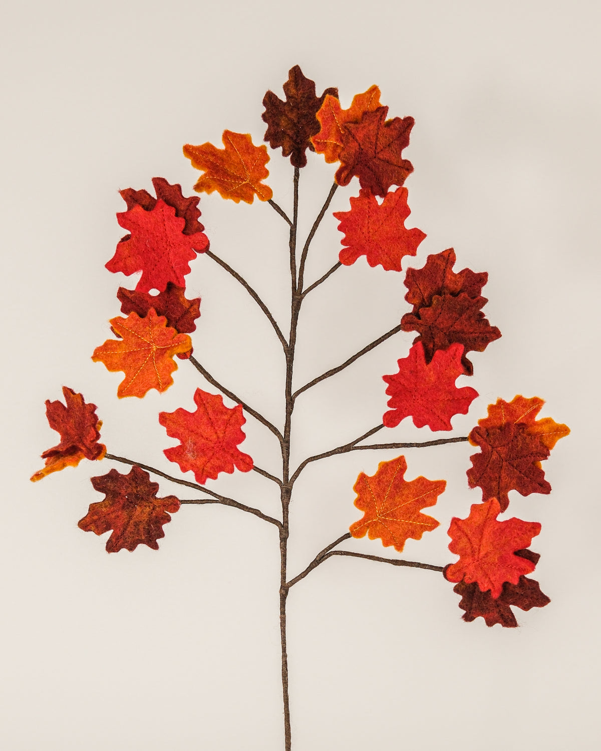 Branche d'automne en feutrine sur un fond blanc.