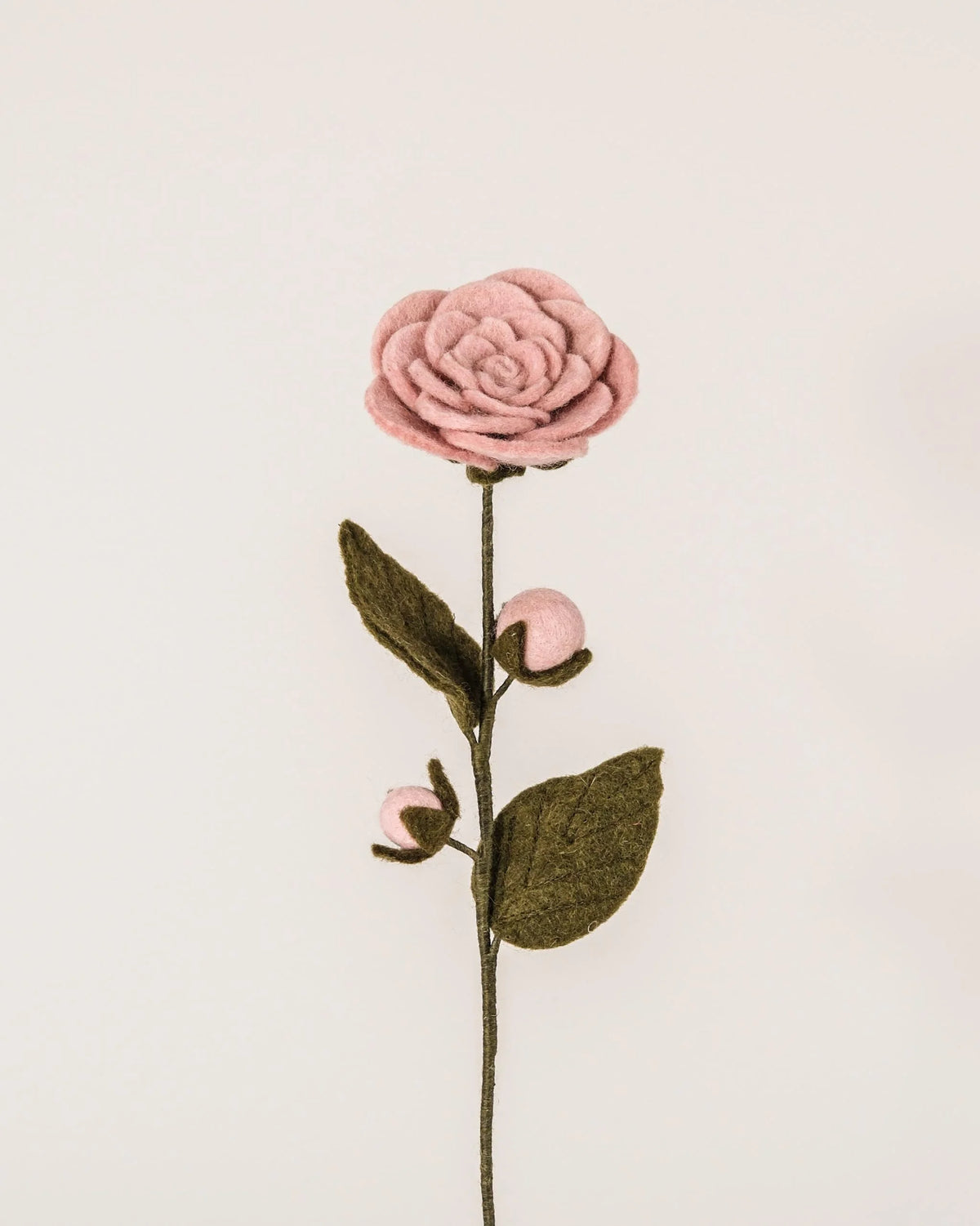 Camélia rose en feutrine sur un fond blanc.