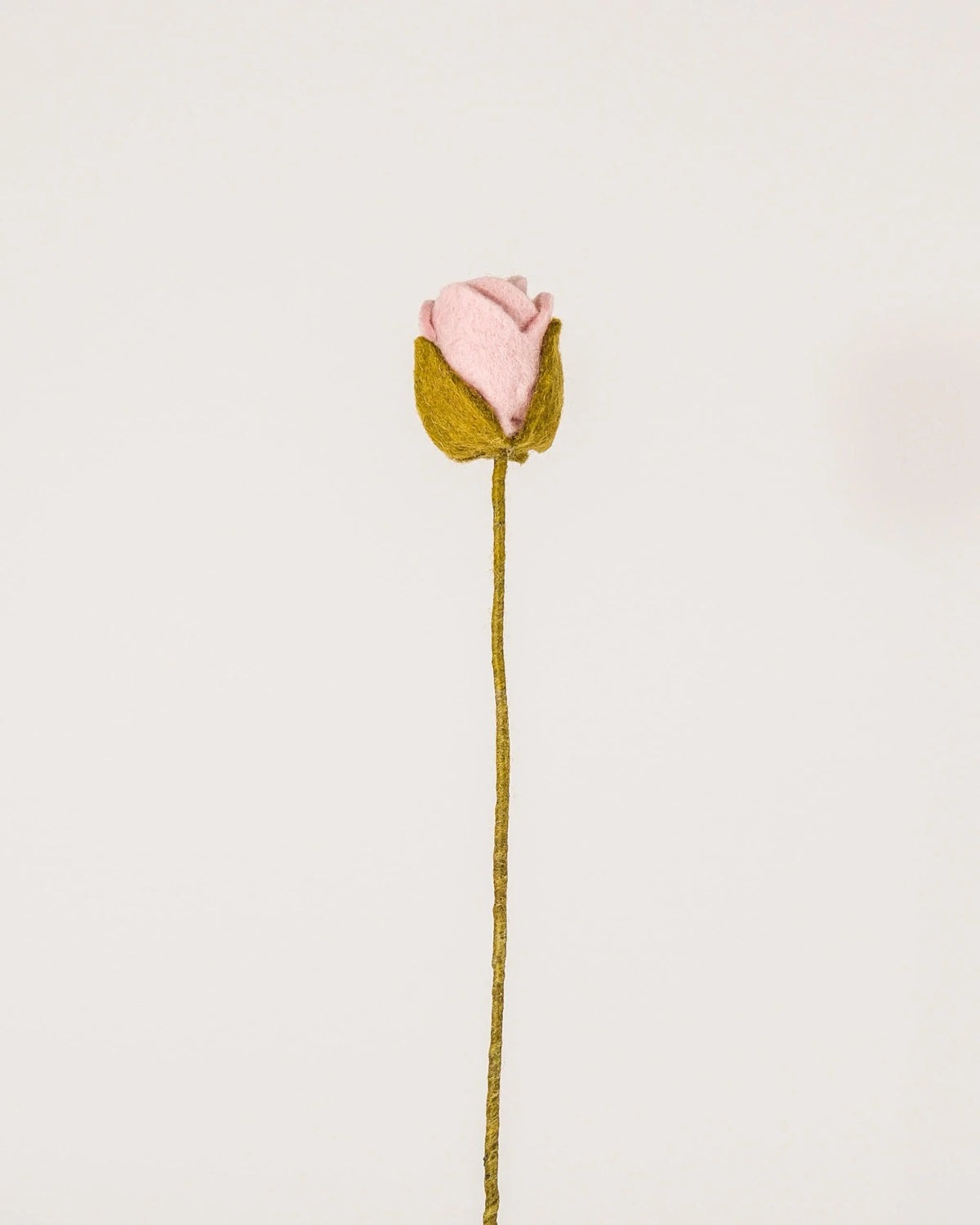 Photo d'une rose rose en feutrine sur un fond blanc.