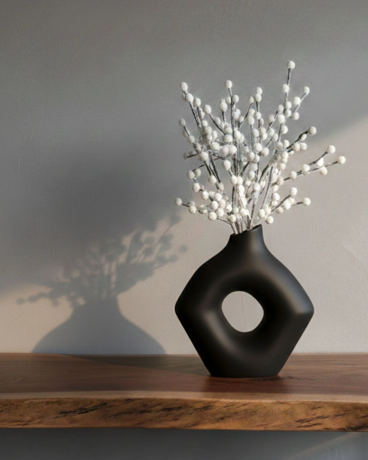 Branche de baie blanche avec vase sur une étagère.