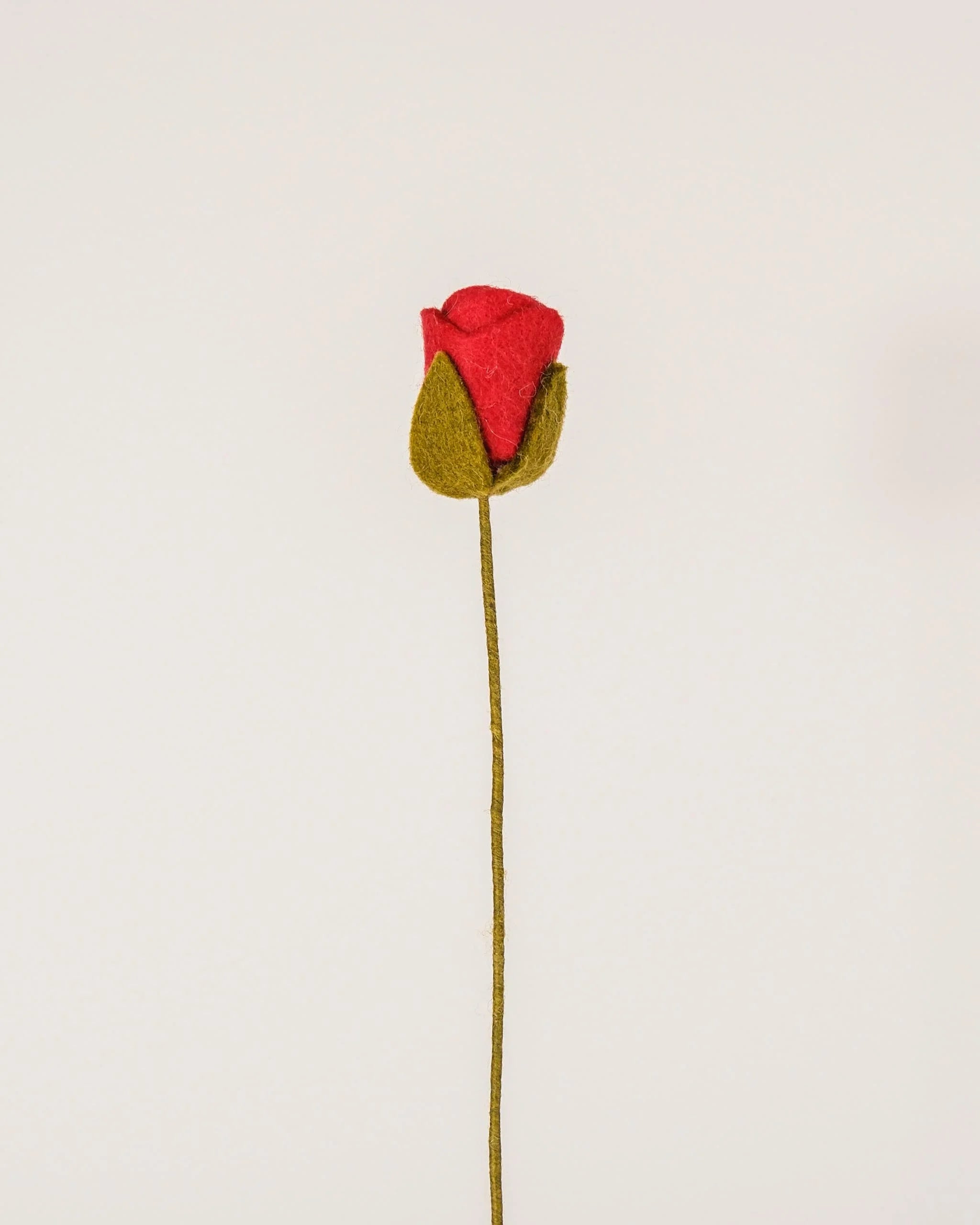 Photo d'une rose rouge en feutrine sur un fond blanc.