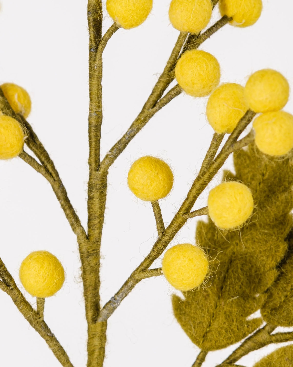 Photo zoom d'un mimosa en feutrine sur un fond blanc.
