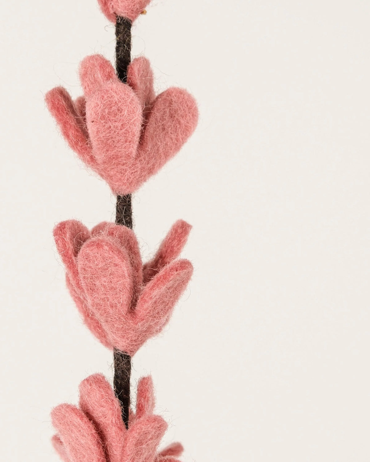 Photo zoom d'une branche de genêt rose en feutrine sur un fond blanc style photo packshot.