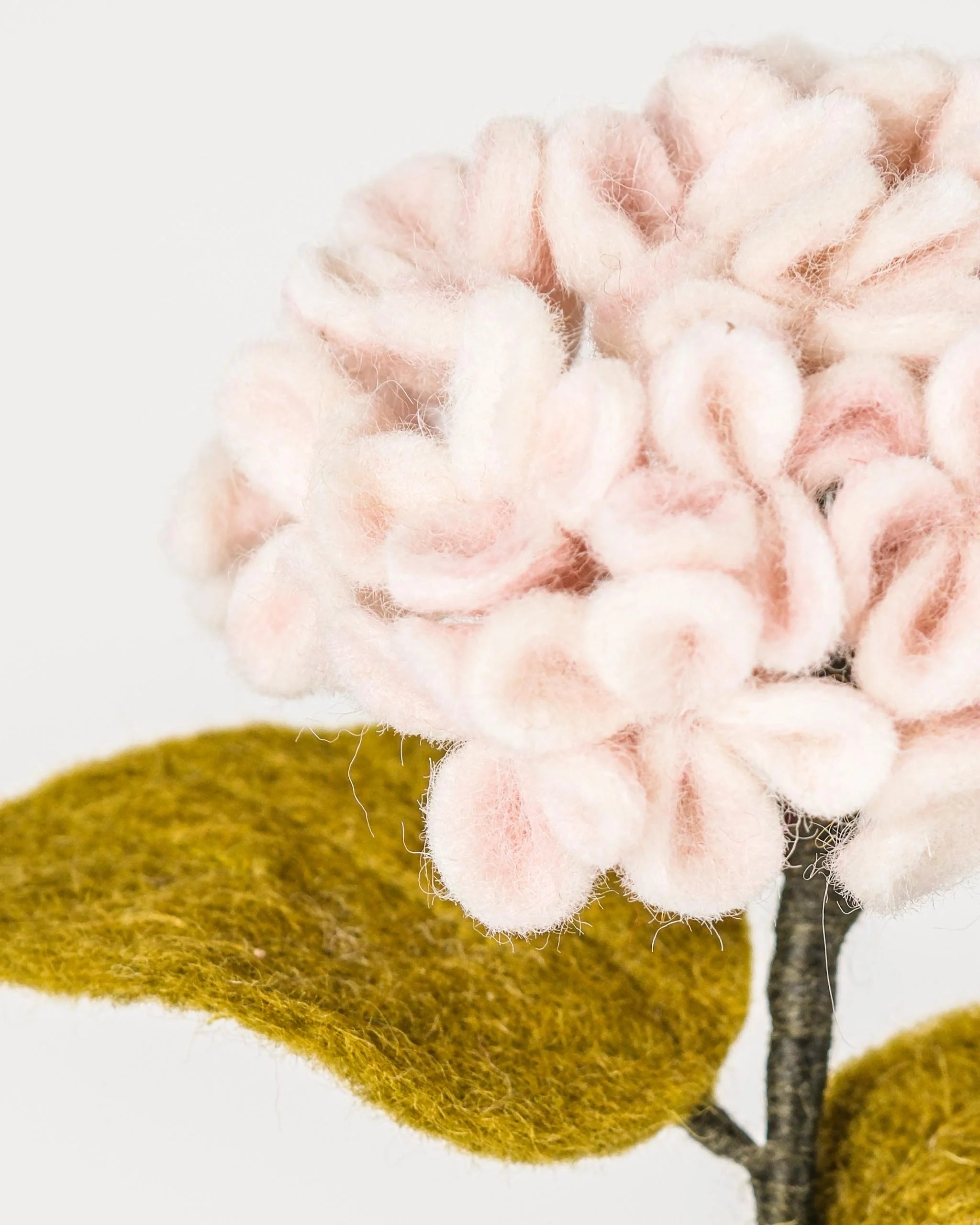 Photo zoom d'une hortensia rose en feutrine sur un fond blanc.