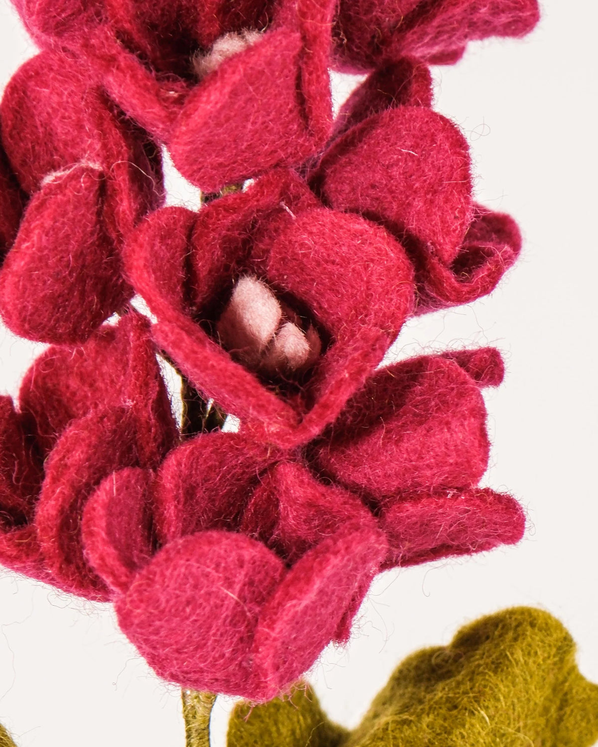 Photo zoom d'une rose trémière rose en feutrine sur un fond blanc style photo packshot.