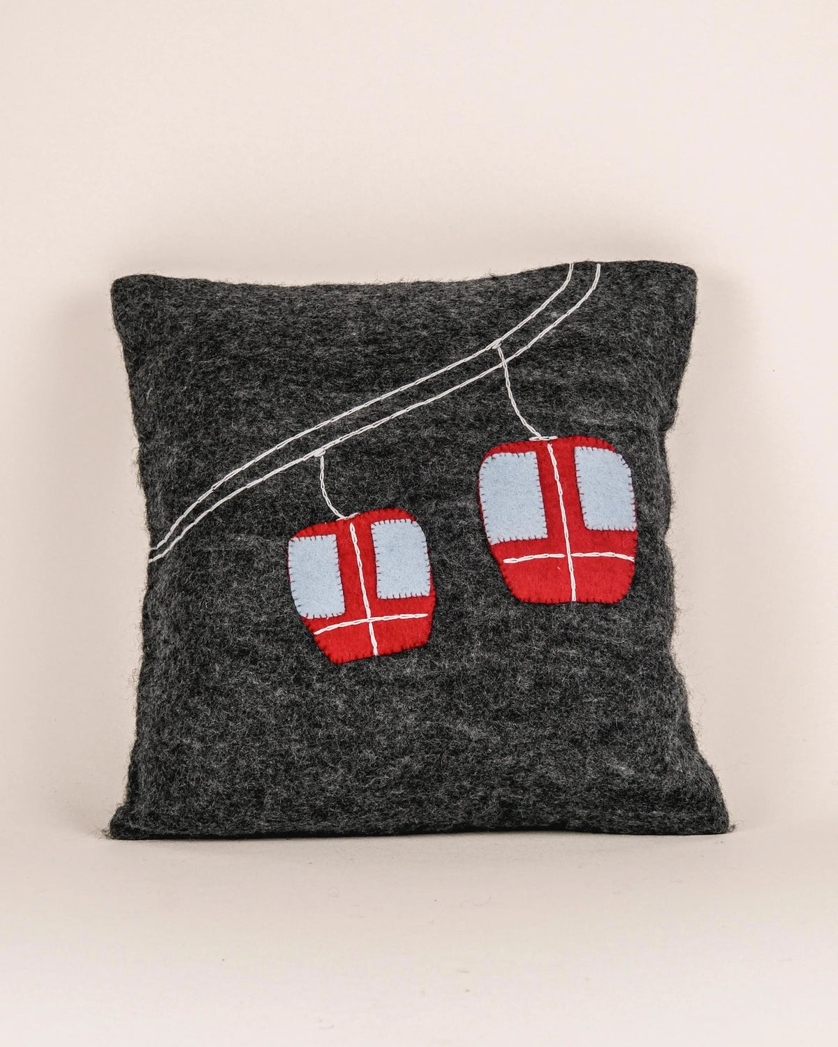 Coussin décoratif télécabine en feutrine sur fond blanc.