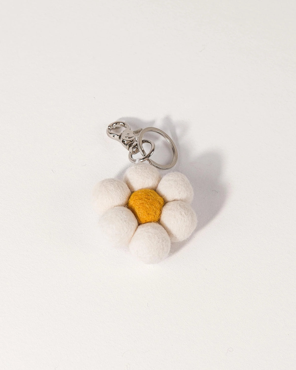 Porte clé marguerite en feutrine sur un fond blanc.