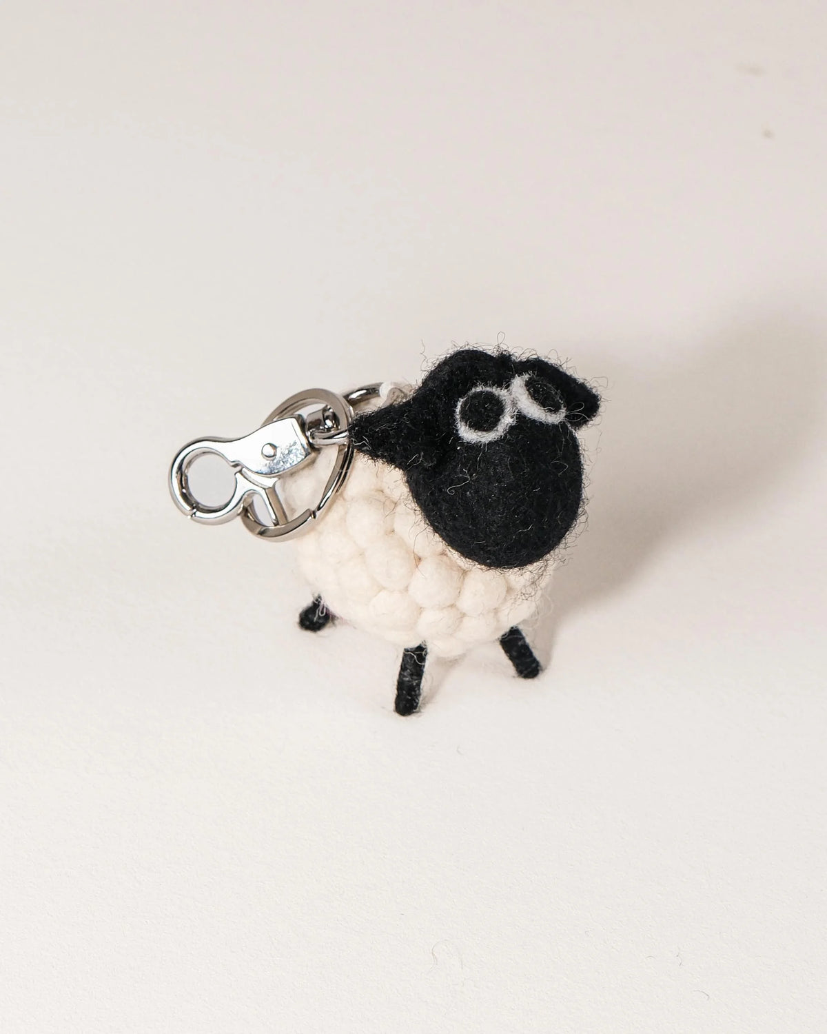 Porte clé mouton tête noir en feutrine sur un fond blanc.