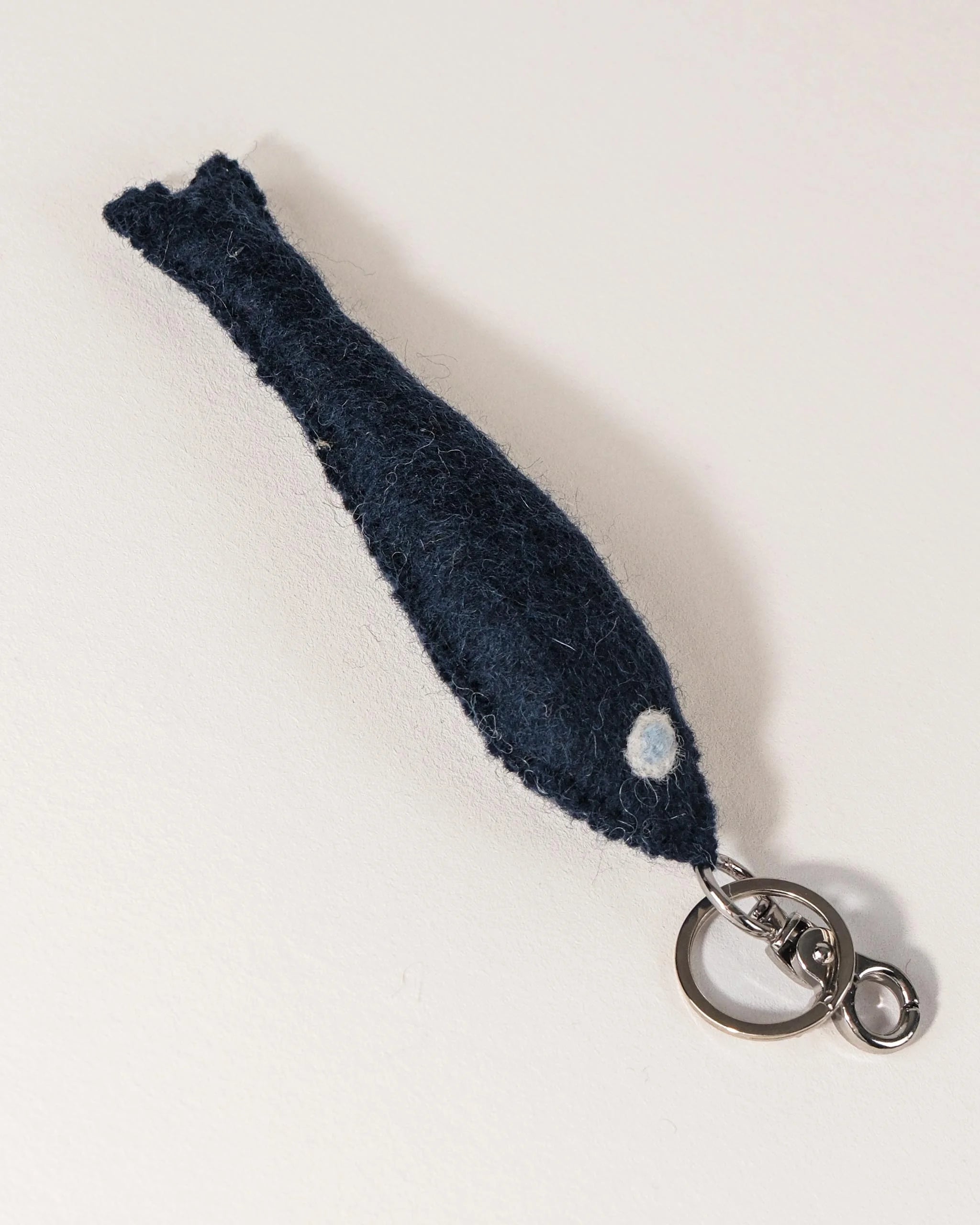 Porte clé petit poisson bleu en feutrine sur un fond blanc.