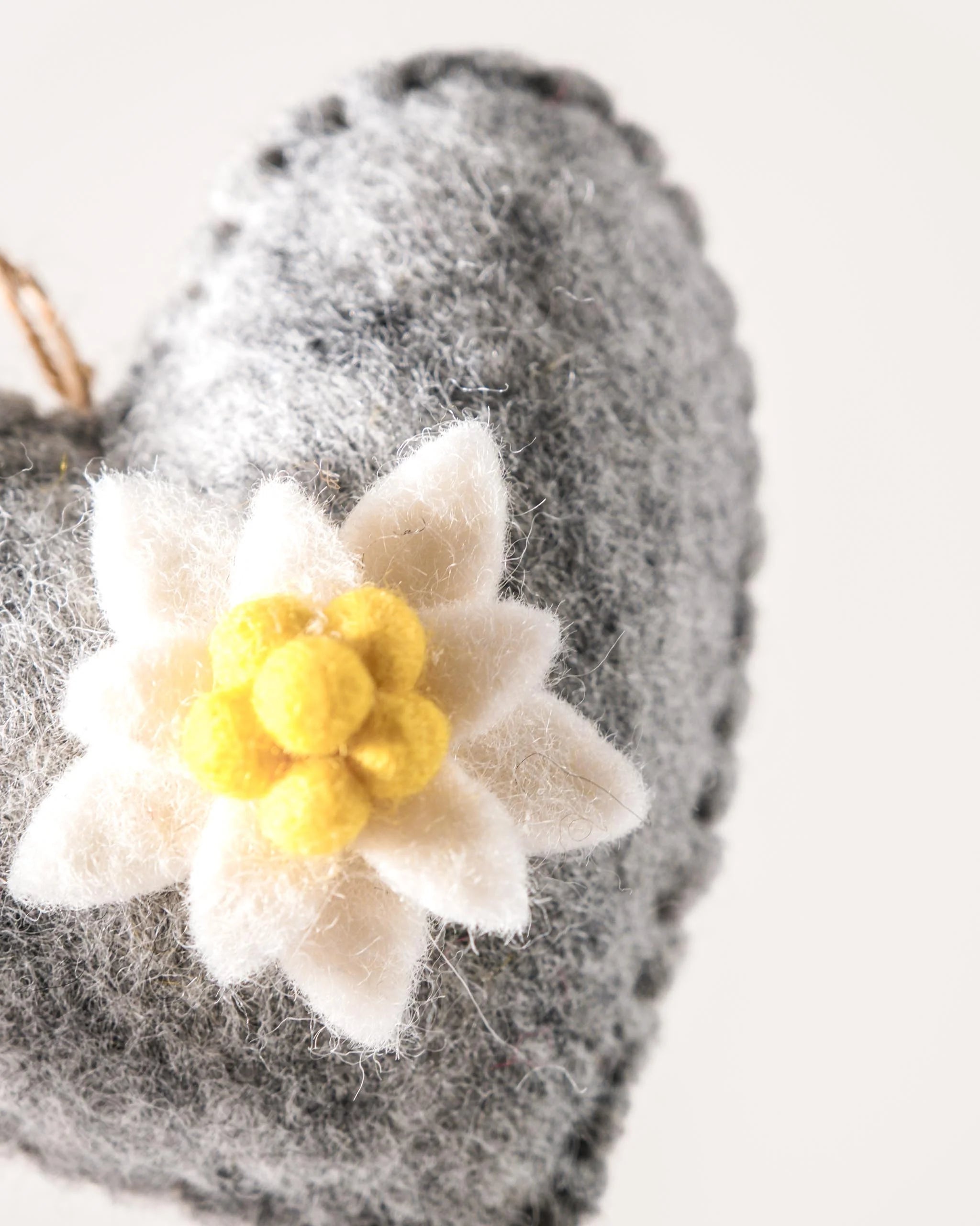 Coeur gris a suspendre avec edelweiss sur fond blanc détail zoom matière.
