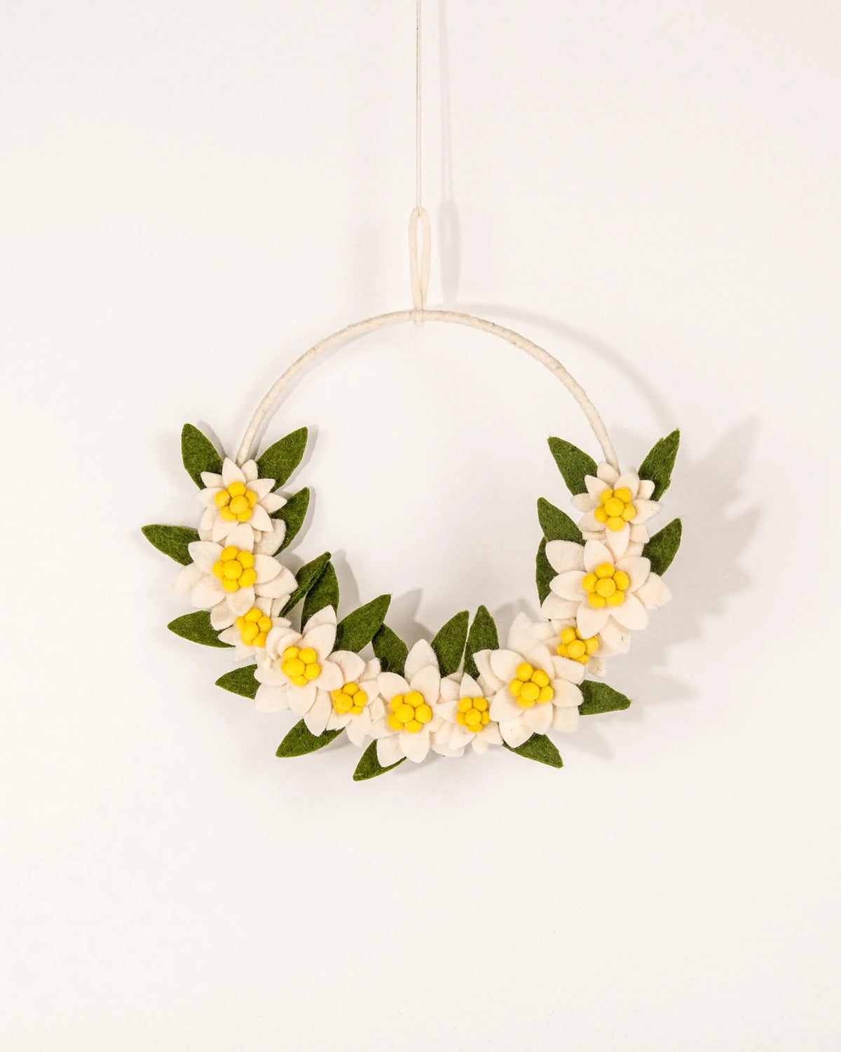 Couronne en feutrine edelweiss sur un mur blanc.