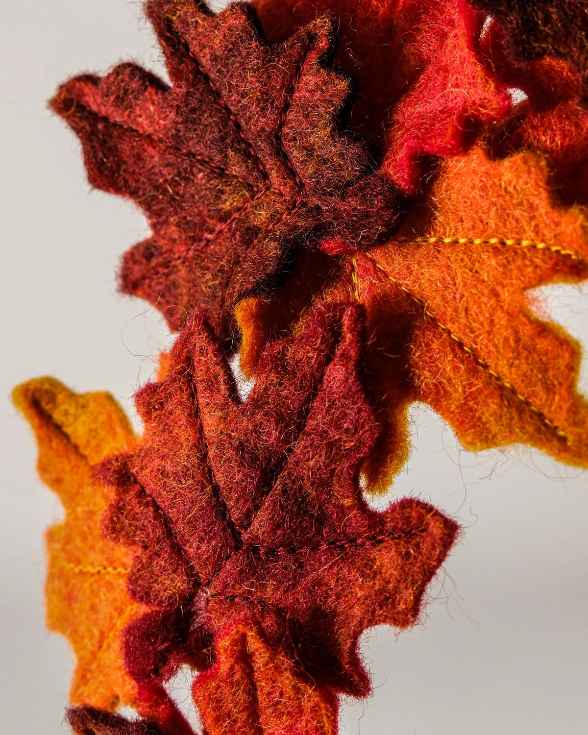 Couronne en feutrine automne sur un mur blanc detail zoom.