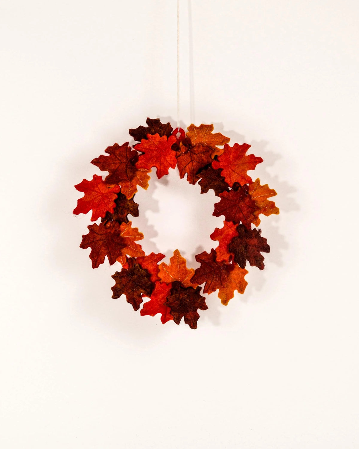 Couronne en feutrine automne sur un mur blanc.