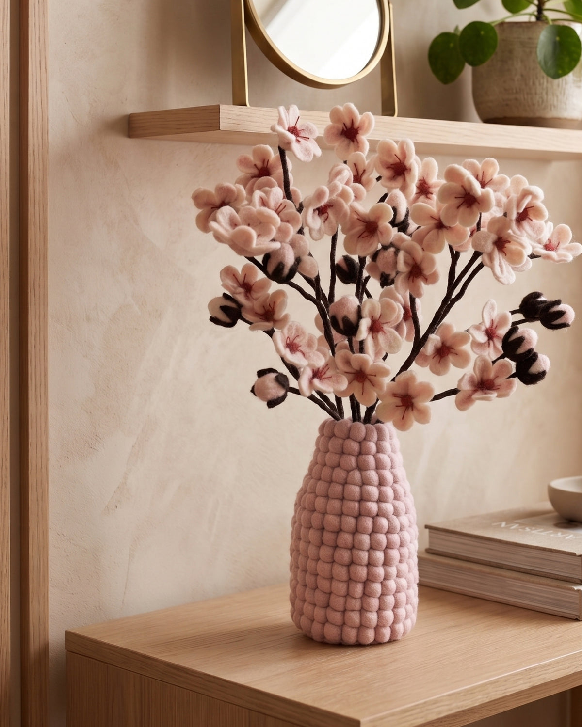 Bouquet de fleurs de cerisier en feutrine dans un vase rose en feutrine.