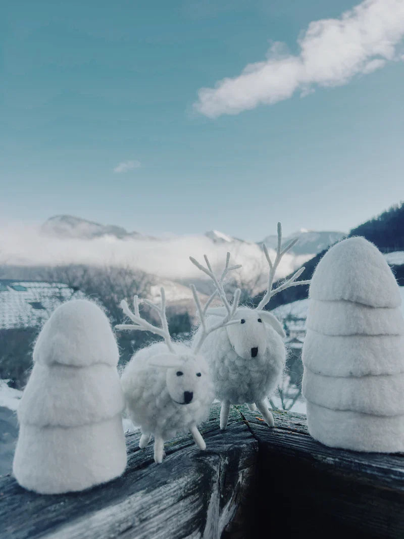Mise en scène hivernale de cerfs blancs New Heidi avec des sapins en laine blanche sur un balcon de montagne.