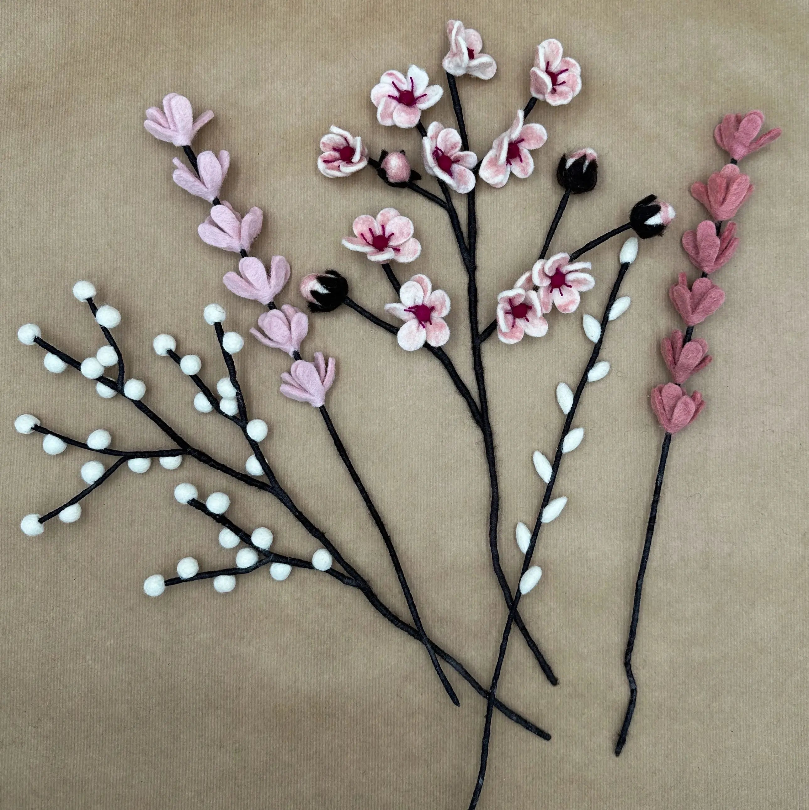 Présentation des différentes tiges artisanales (cerisier, genêts, saule, baies) du bouquet Douceur de Cerisier.