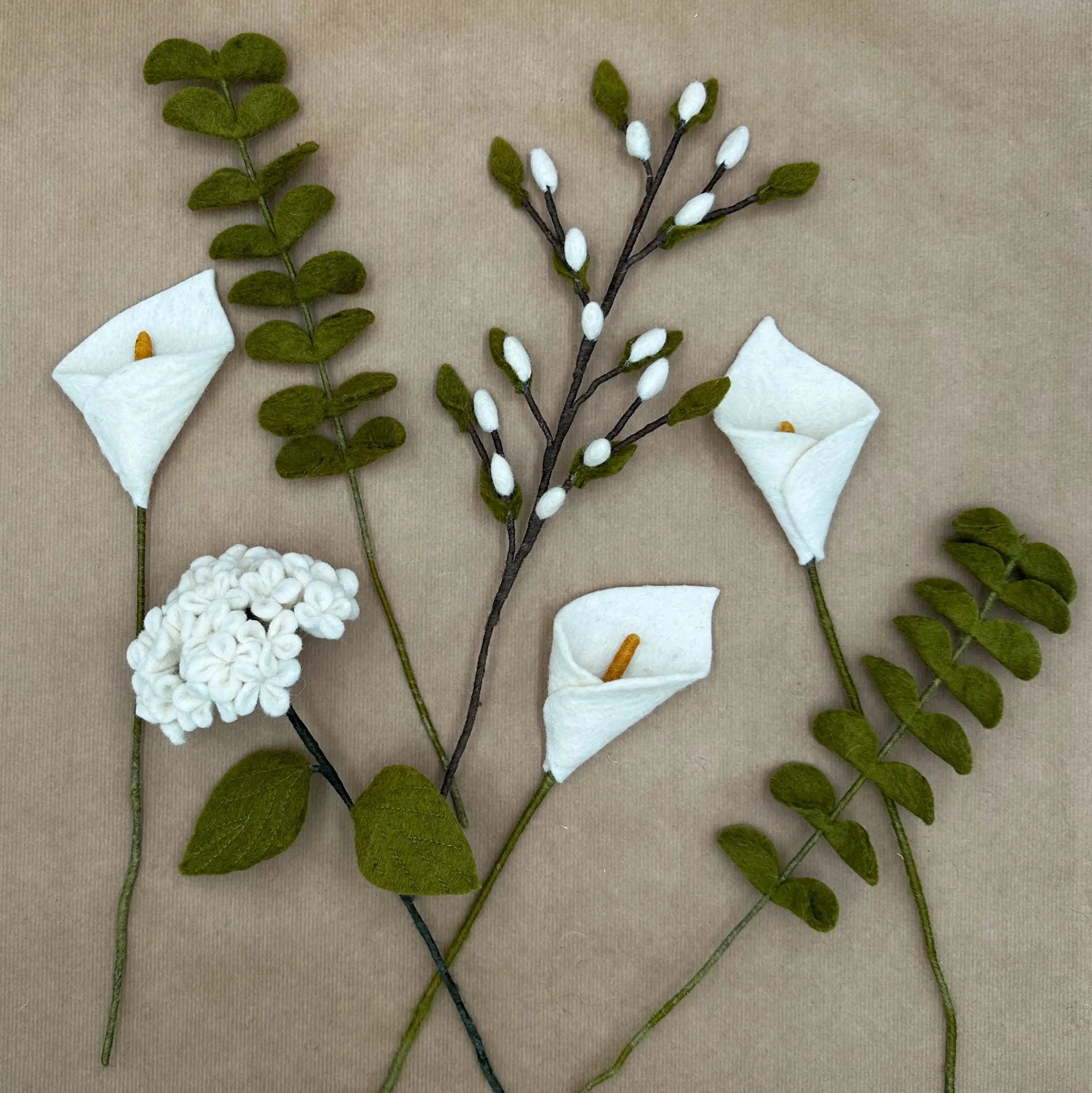 Présentation des sept tiges artisanales (arums, hortensia, eucalyptus, bourgeons) du bouquet Pureté de l'Arum.