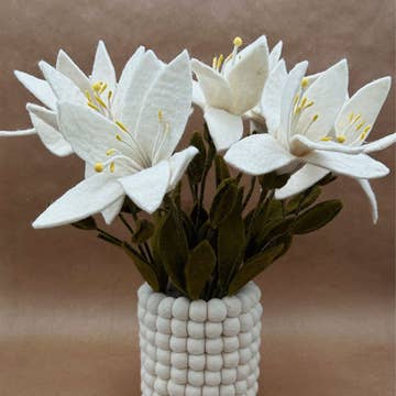 Grande composition de lys en feutrine New Heidi dans un vase décoratif blanc à pompons.