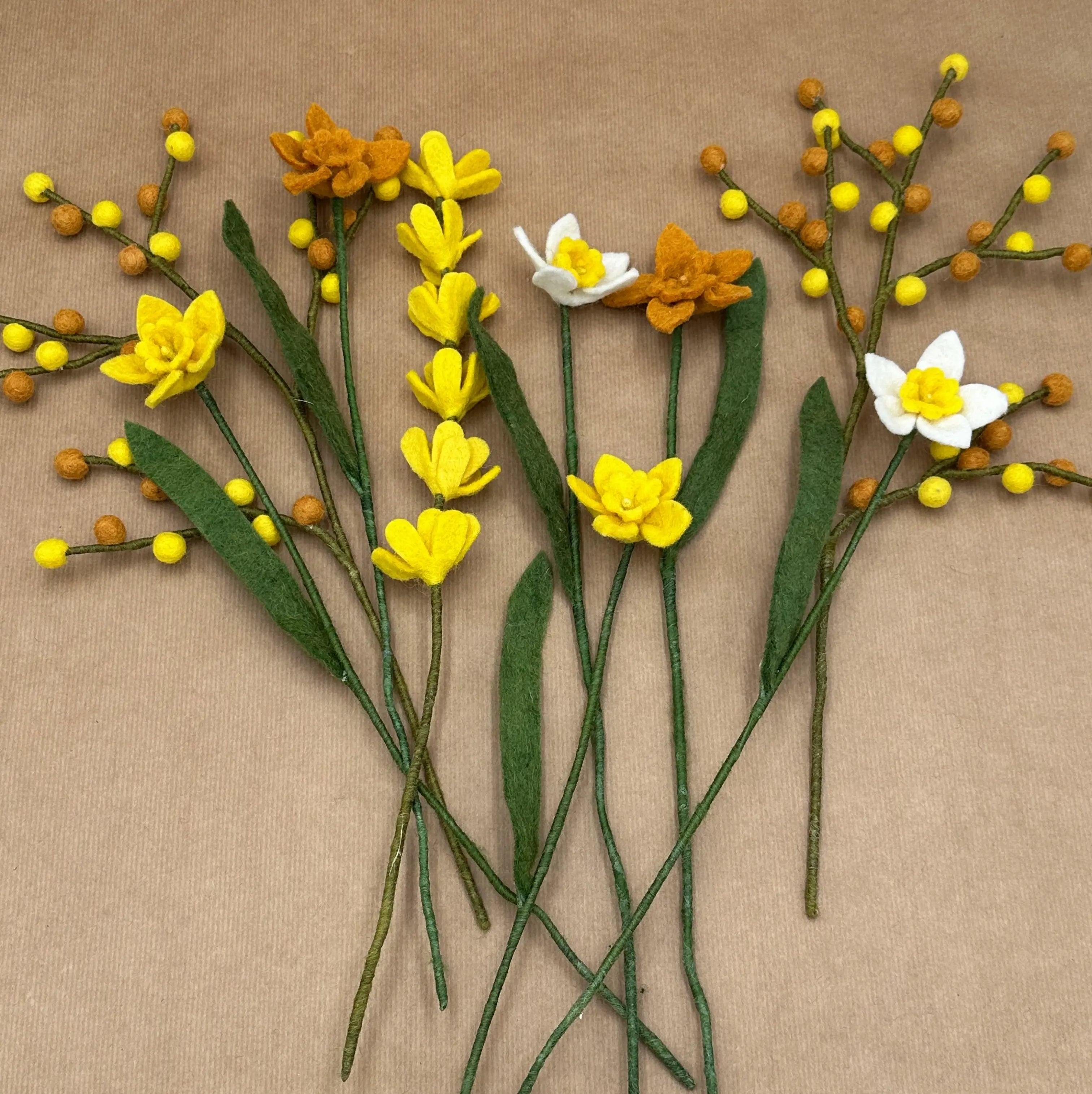 Présentation des différentes tiges artisanales (jonquilles multicolores, baies, genêt) du bouquet Solaire d'Alpage.