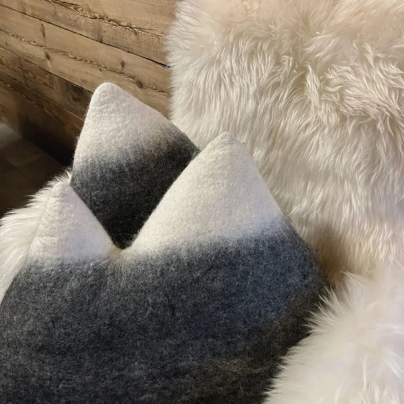 Coussin montagne double New Heidi posé sur une peau de mouton blanche pour une ambiance cocooning.