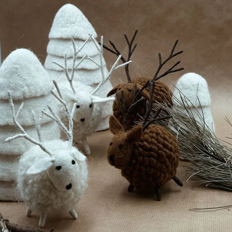 Mise en scène de cerfs en feutrine marron et blanc New Heidi avec des sapins artisanaux en laine.