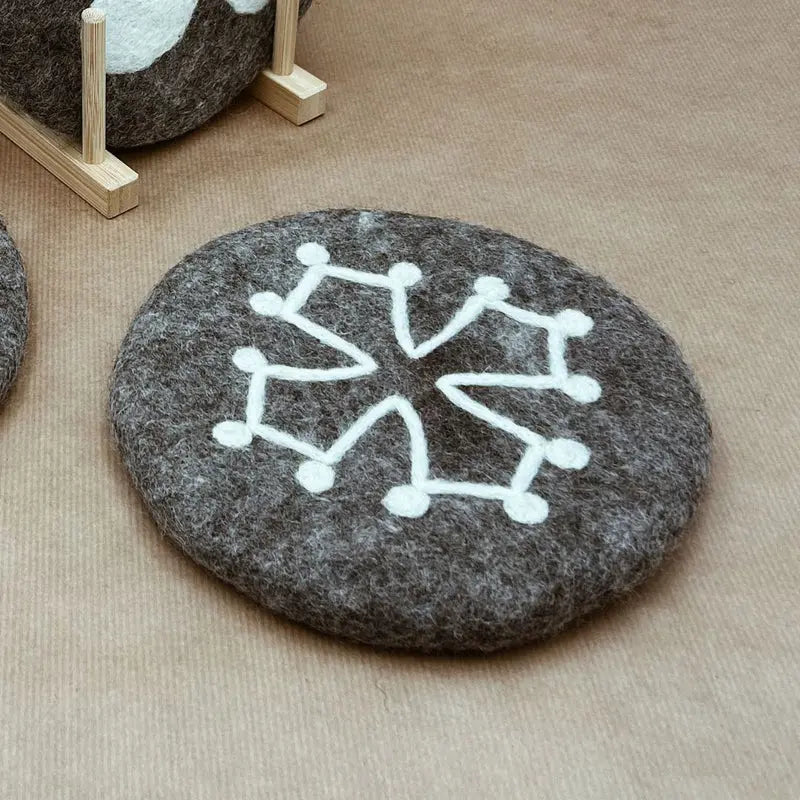 Dessous de plat artisanal motif Croix Occitane New Heidi présenté sur un fond kraft protecteur.