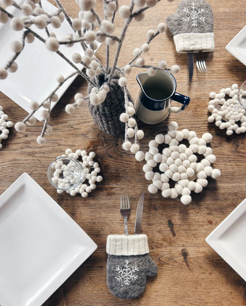 Présentation d'une table de fête avec le gant à couverts flocon New Heidi et des accessoires en laine.