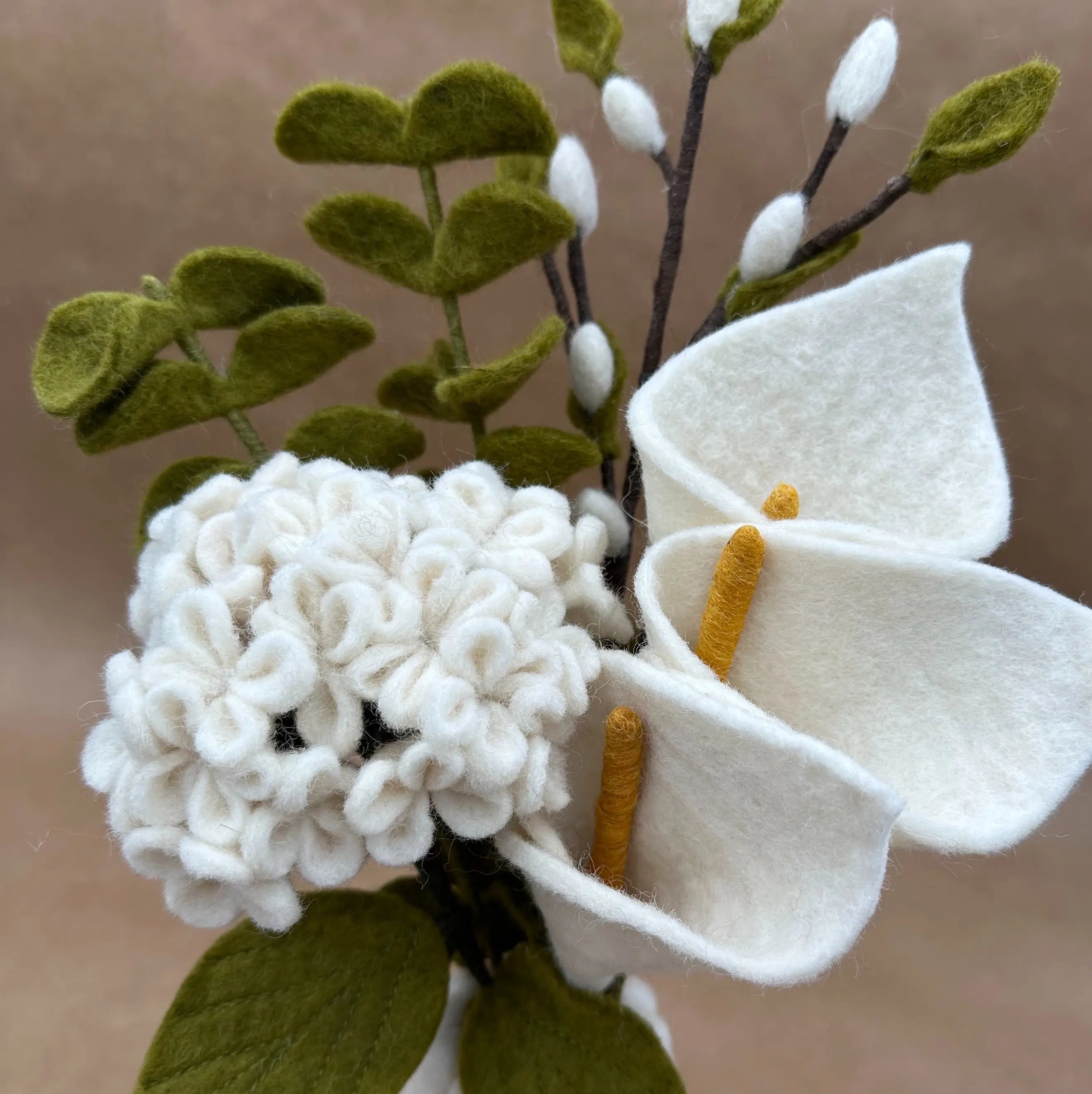 Gros plan sur les détails artisanaux des arums blancs et de l'hortensia en laine New Heidi.