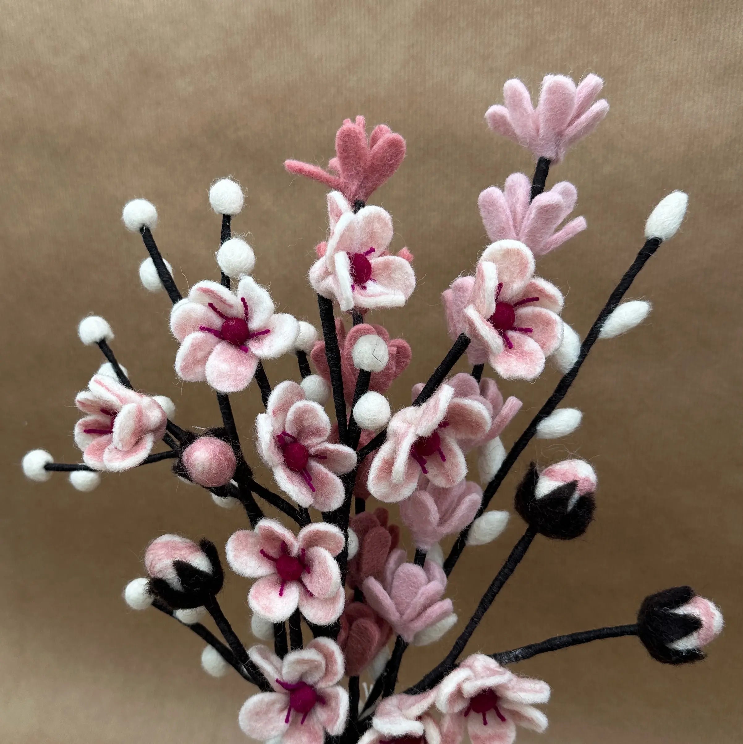 Gros plan sur les détails artisanaux des fleurs de cerisier et des genêts en laine New Heidi.