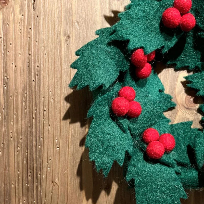 Détail des baies rouges et feuilles de houx faites main en feutrine de laine.