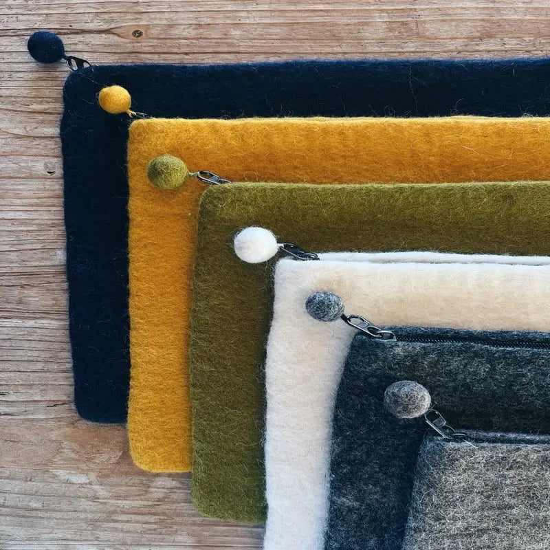 Détail des finitions artisanales et fermetures éclair avec pompons en feutre de laine New Heidi.