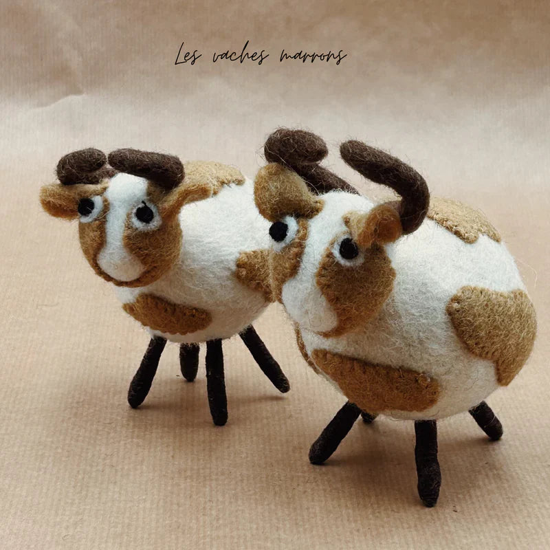 Mise en scène de deux vaches boules marron New Heidi faites à la main en laine bouillie.