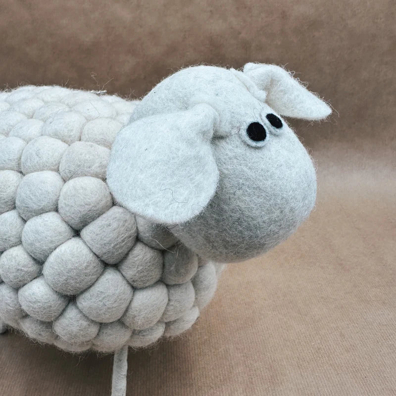 Gros plan sur la tête du mouton géant New Heidi en laine feutrée avec sa petite clochette dorée.