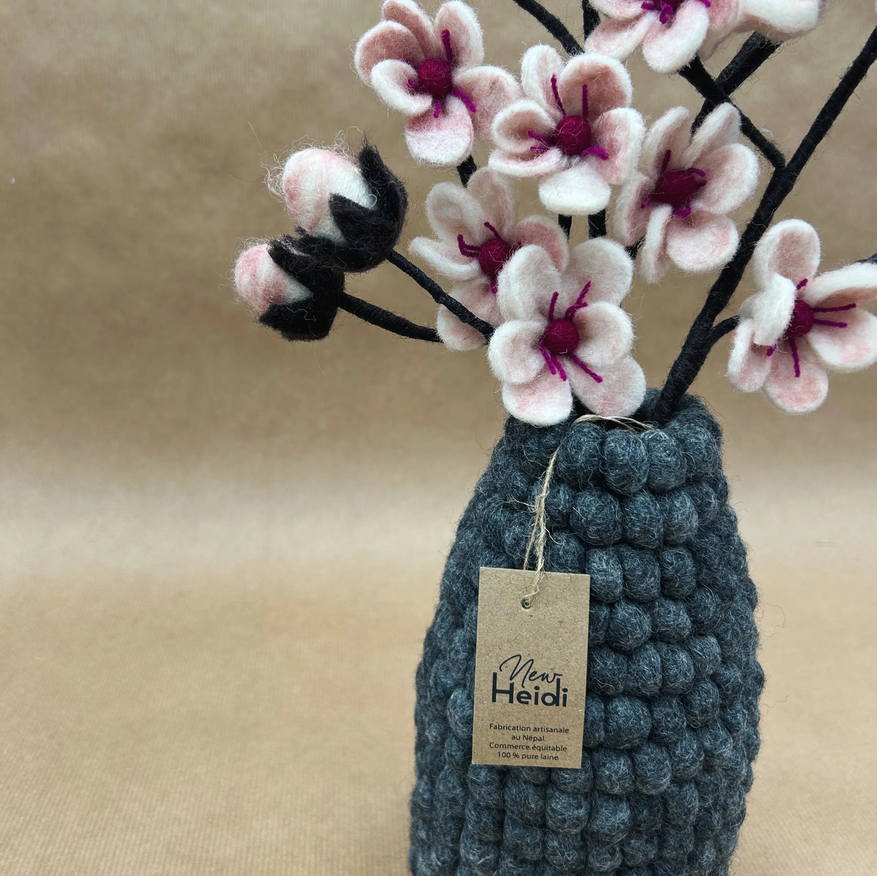 Gros plan sur le vase en feutrine anthracite New Heidi avec son étiquette artisanale certifiant le fait main.
